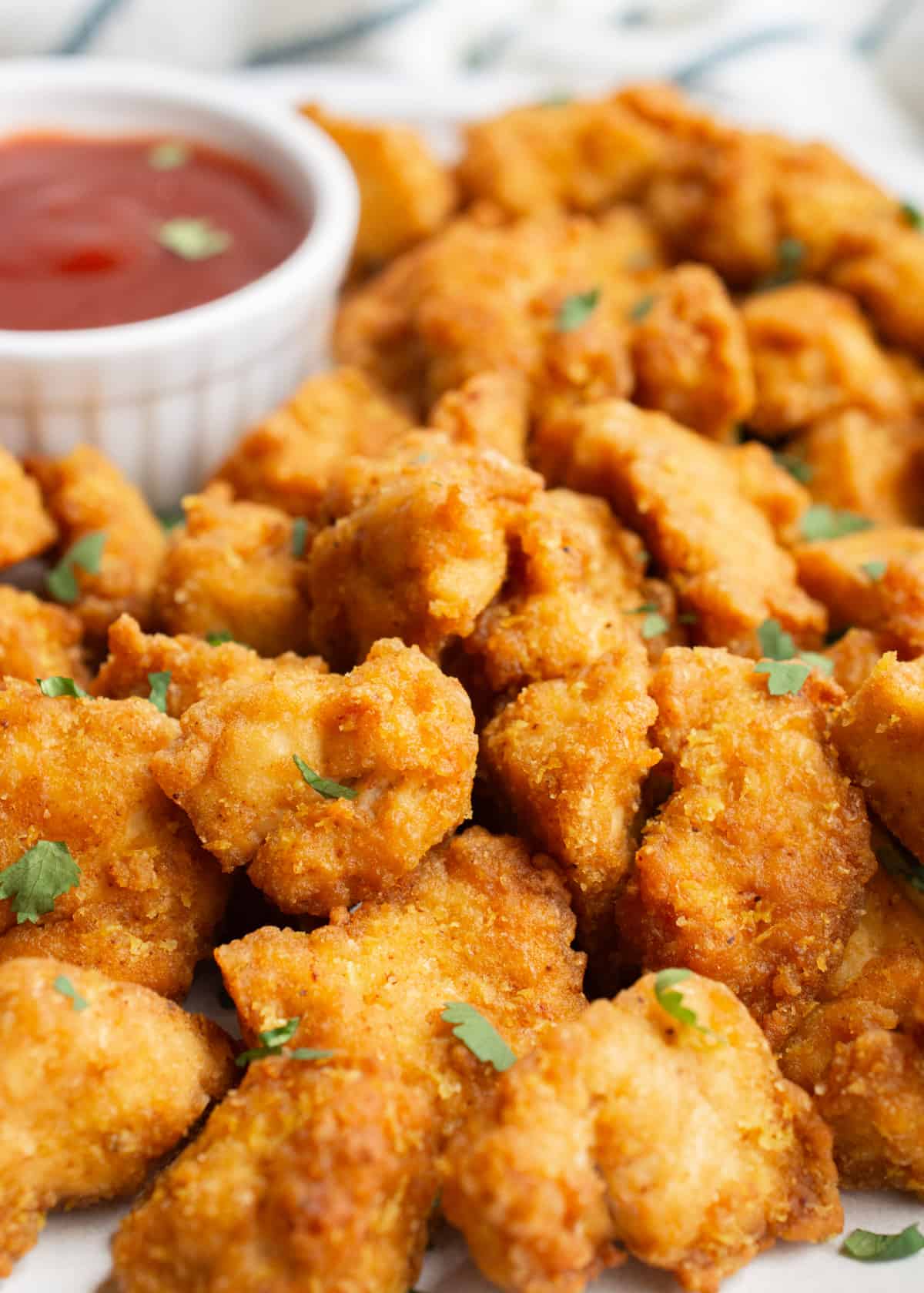 A pile of tofu popcorn nuggets with small bowl of dipping sauce.