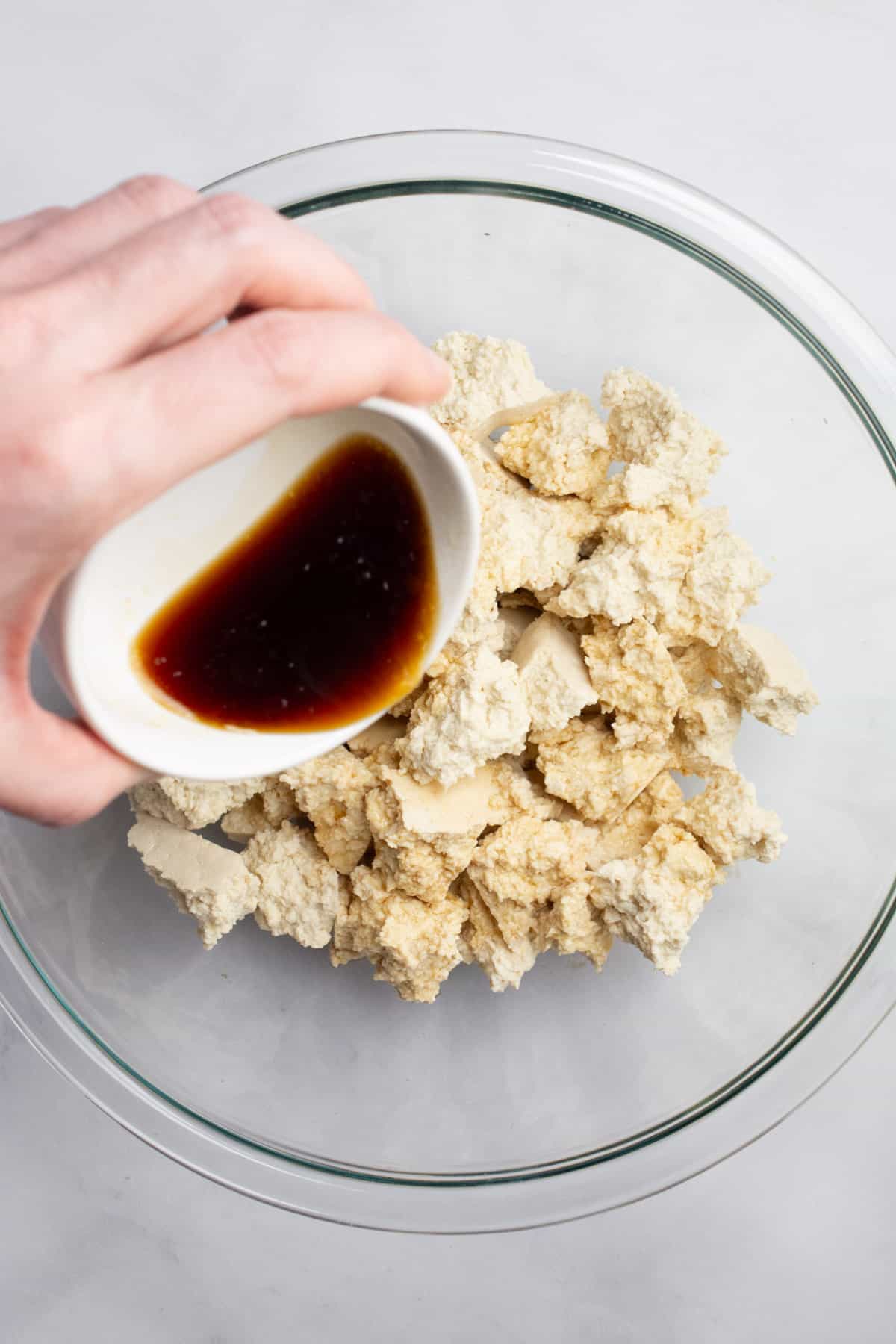 Soy sauce mix being poured over chunks of tofu.