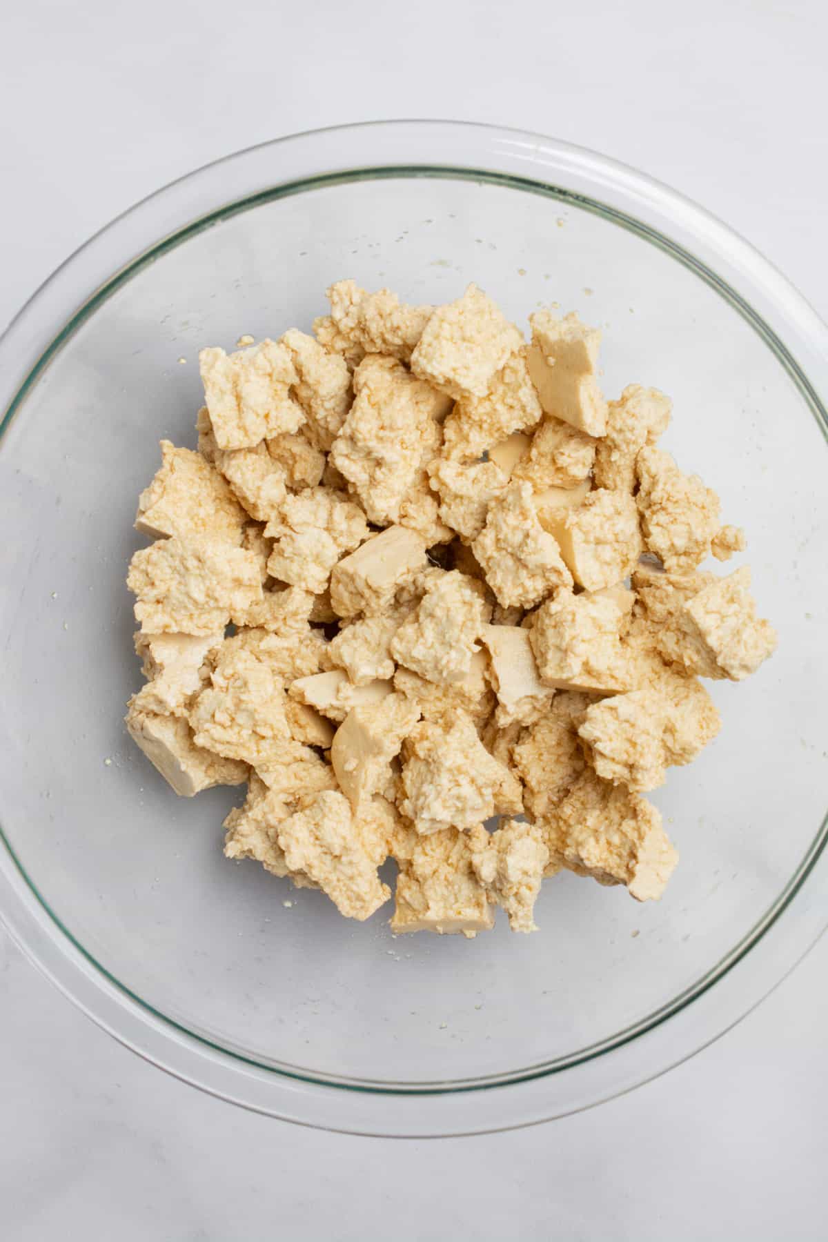 A glass bowl with chunks of tofu tossed with a soy sauce mix.