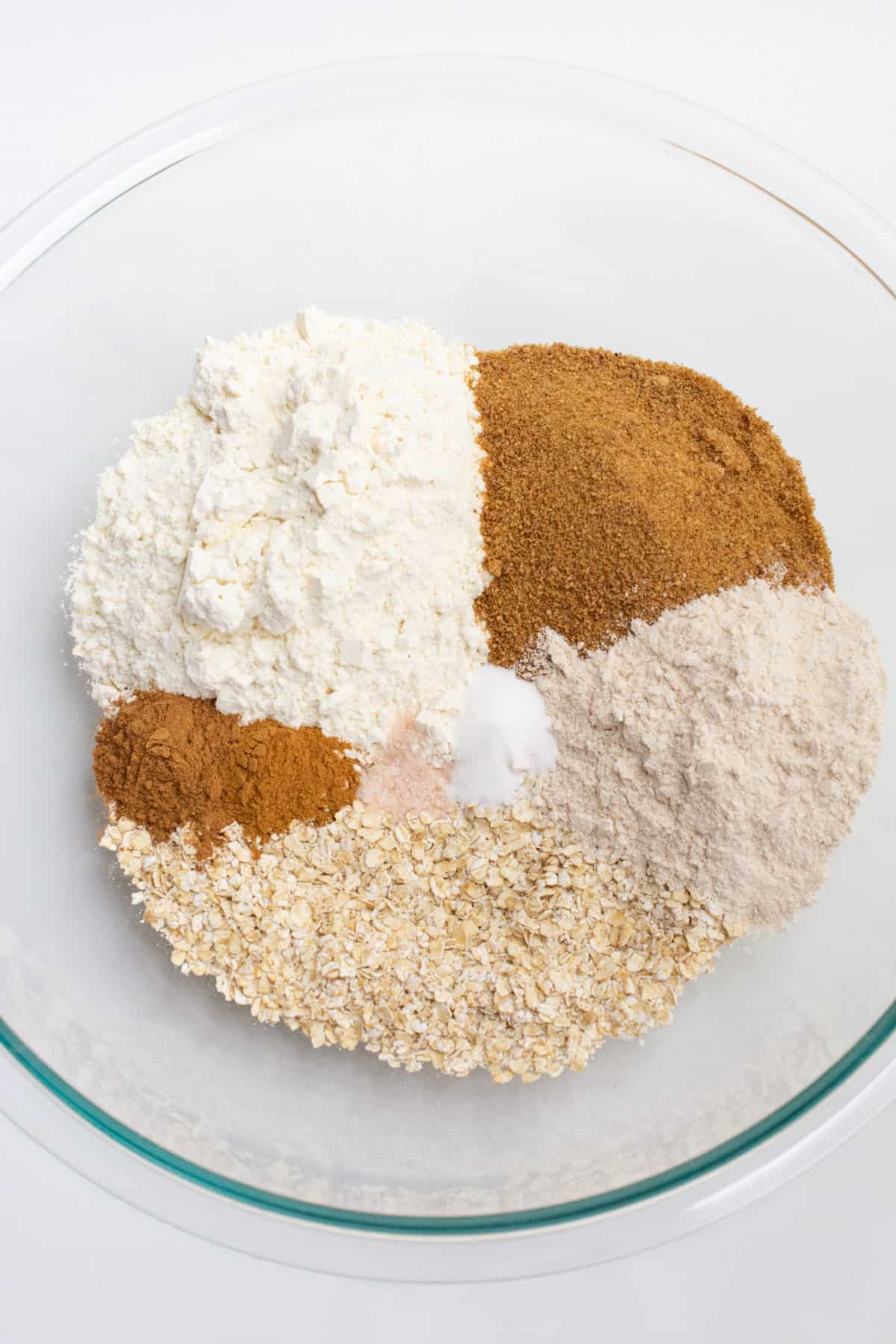 Dry oatmeal cookie ingredients in a glass bowl.