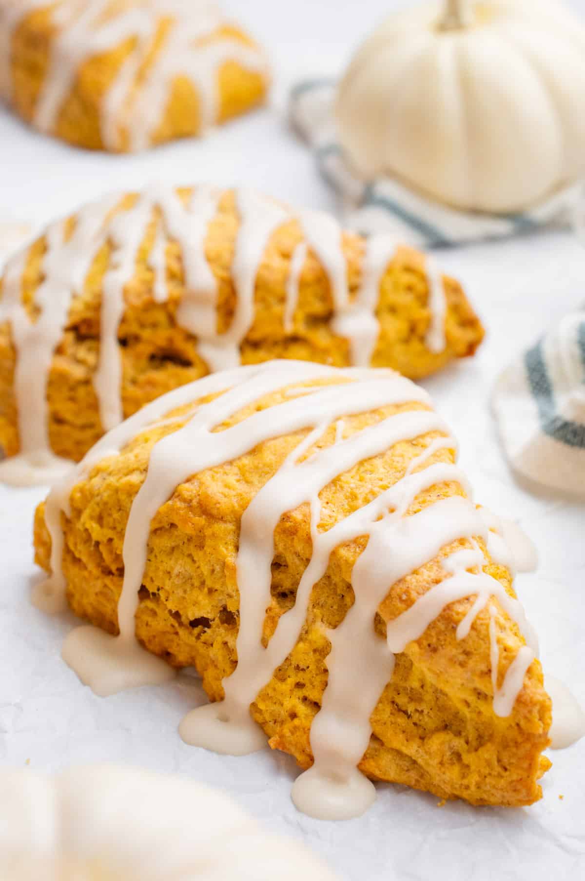 Two vegan pumpkin scones drizzled with a glaze.