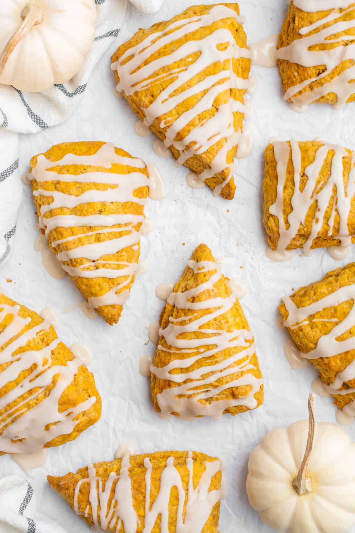 Eight vegan pumpkin scones drizzled with icing.