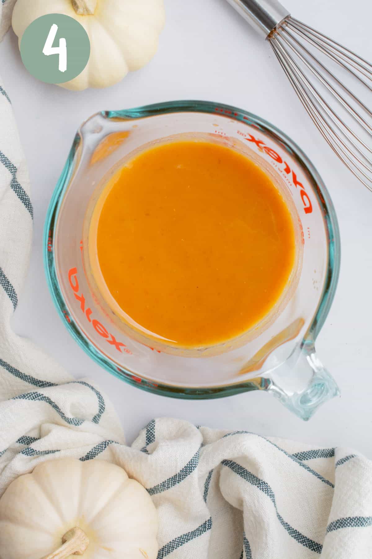 A glass measuring cup with almond milk and pumpkin purée.