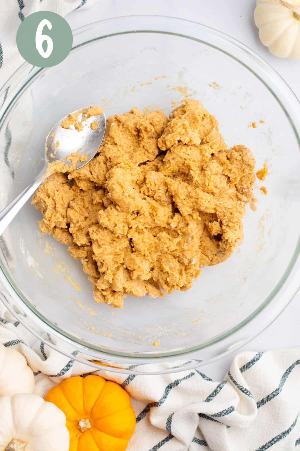 A bowl of vegan pumpkin scone dough with a mixing spoon.