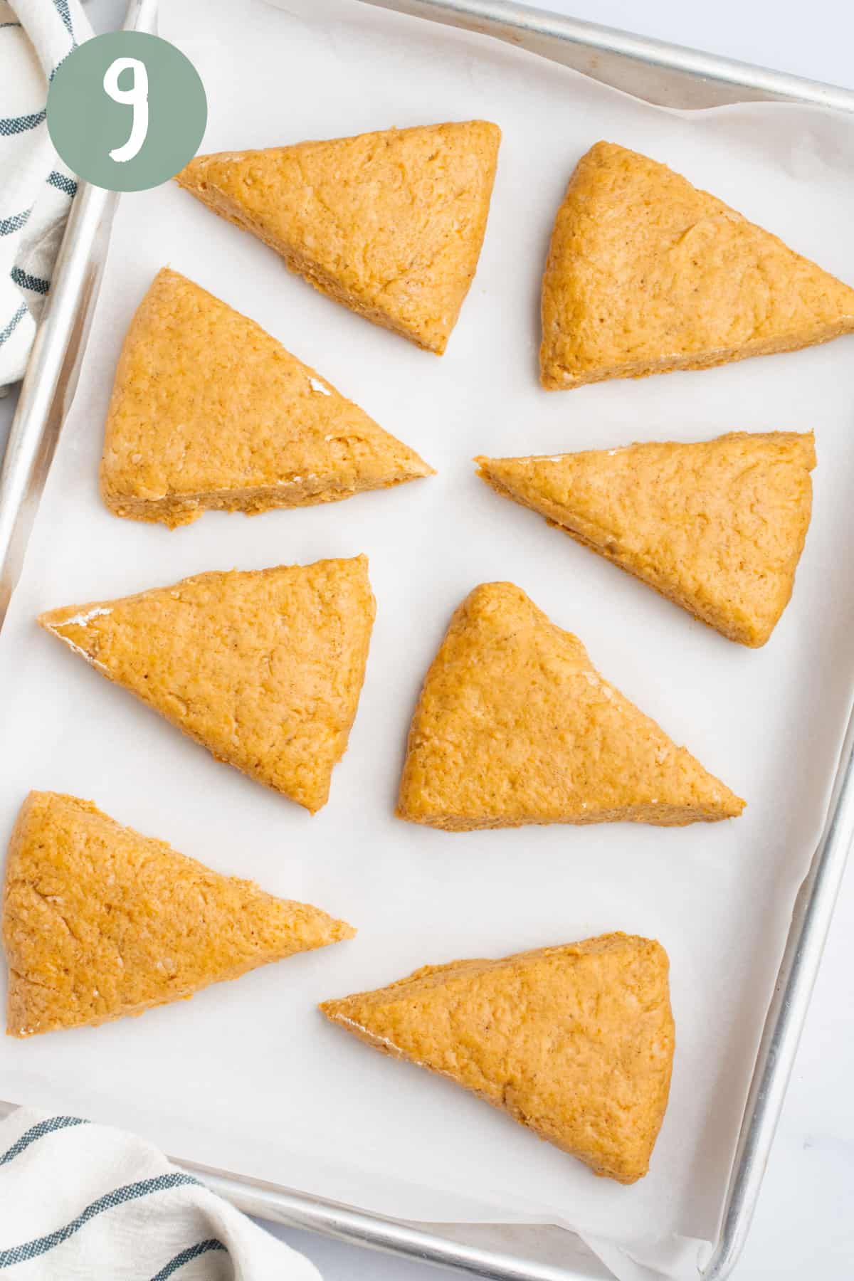 Vegan pumpkin scones dough triangles on a baking sheet lined with parchment paper.