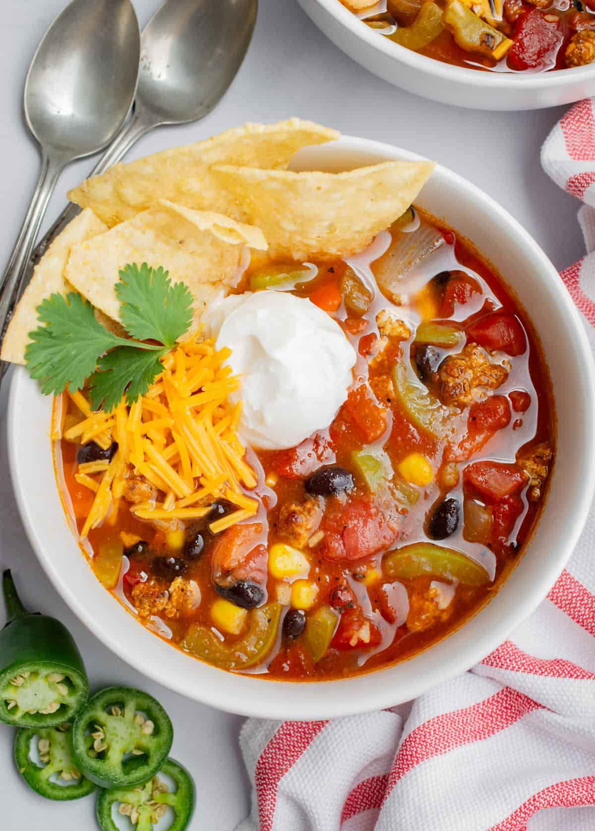 Looking down a a bowl of taco soup topped with vegan sour cream, vegan cheese shreds, cilantro leaves, and tortilla chips.