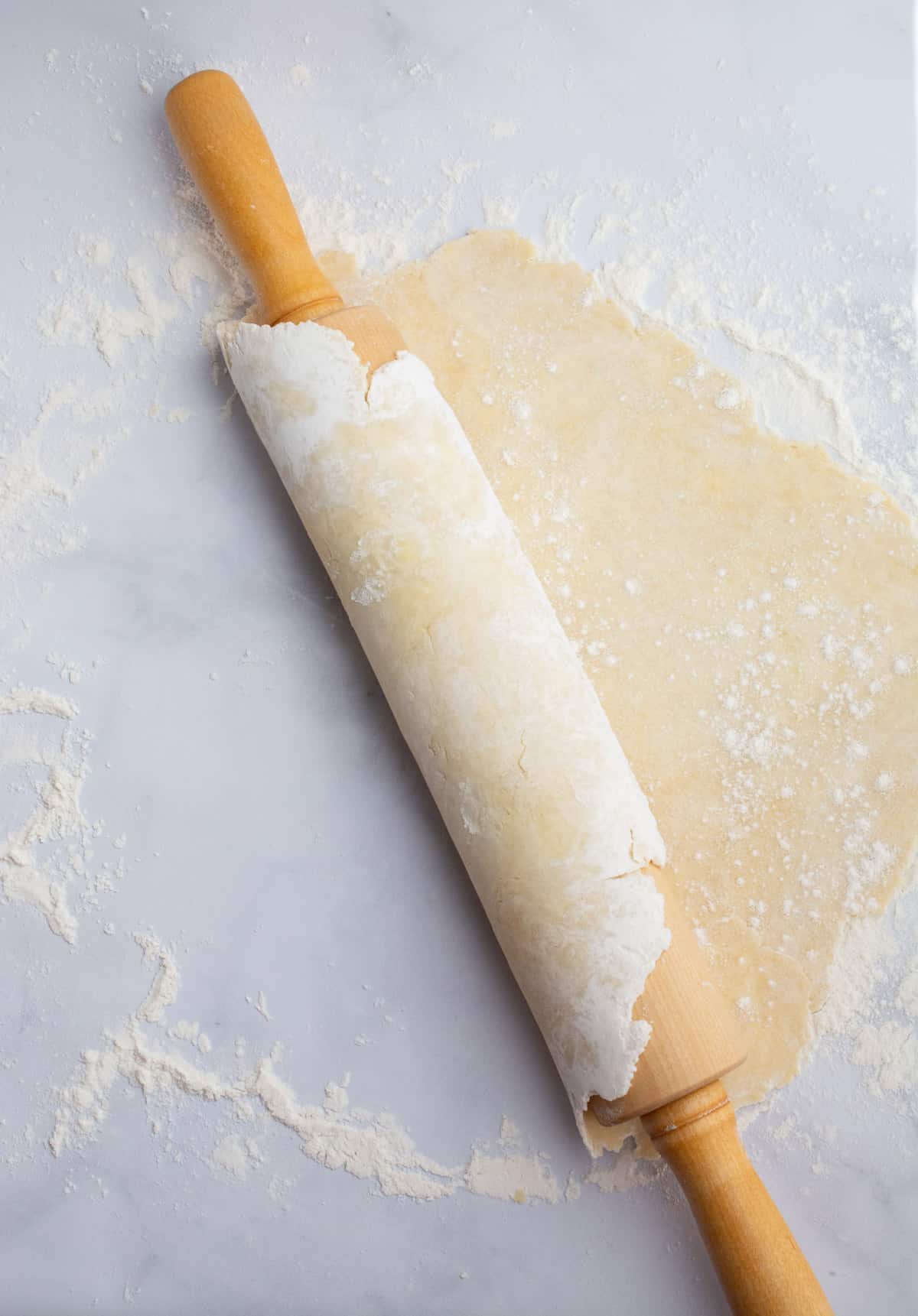 A rolling pin with pie dough rolled around it.