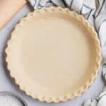 Vegan pie crust dough with crimped edges in a pie dish.