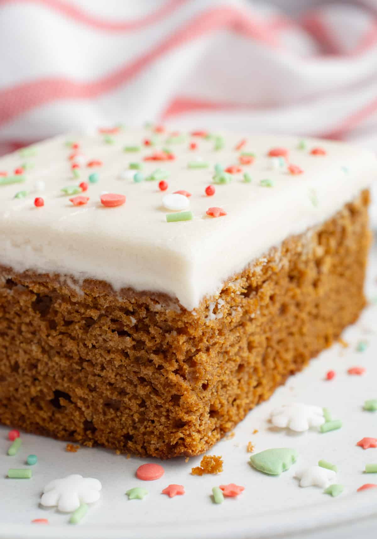 Vegan gingerbread cake topped with frosting and festive sprinkles.