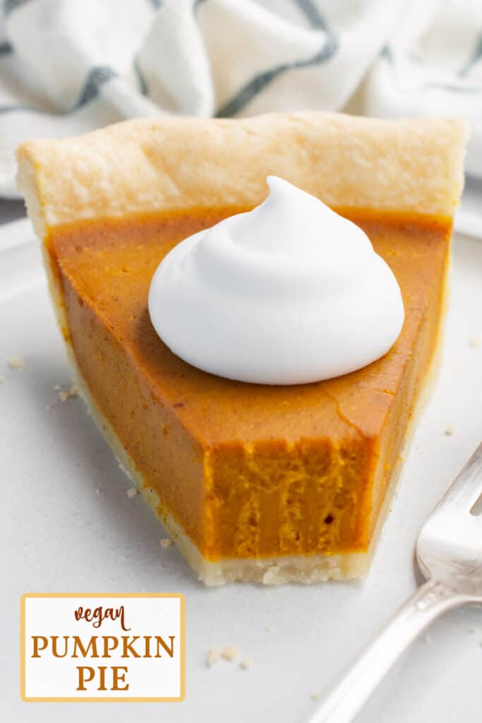 A slice of pumpkin pie topped with coconut whip and a piece taken off with a fork.