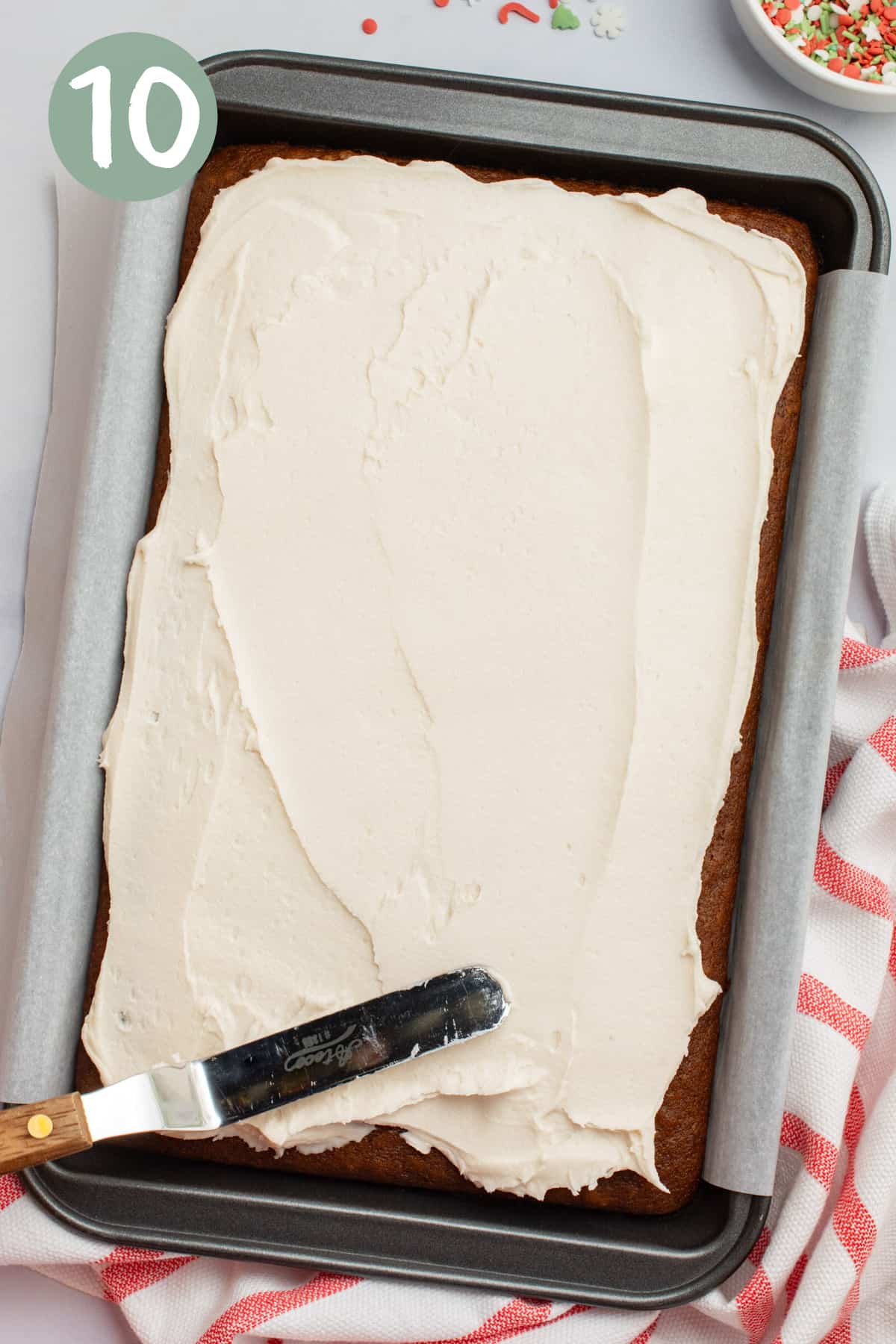Frosting being spread across a cake with a spatula.