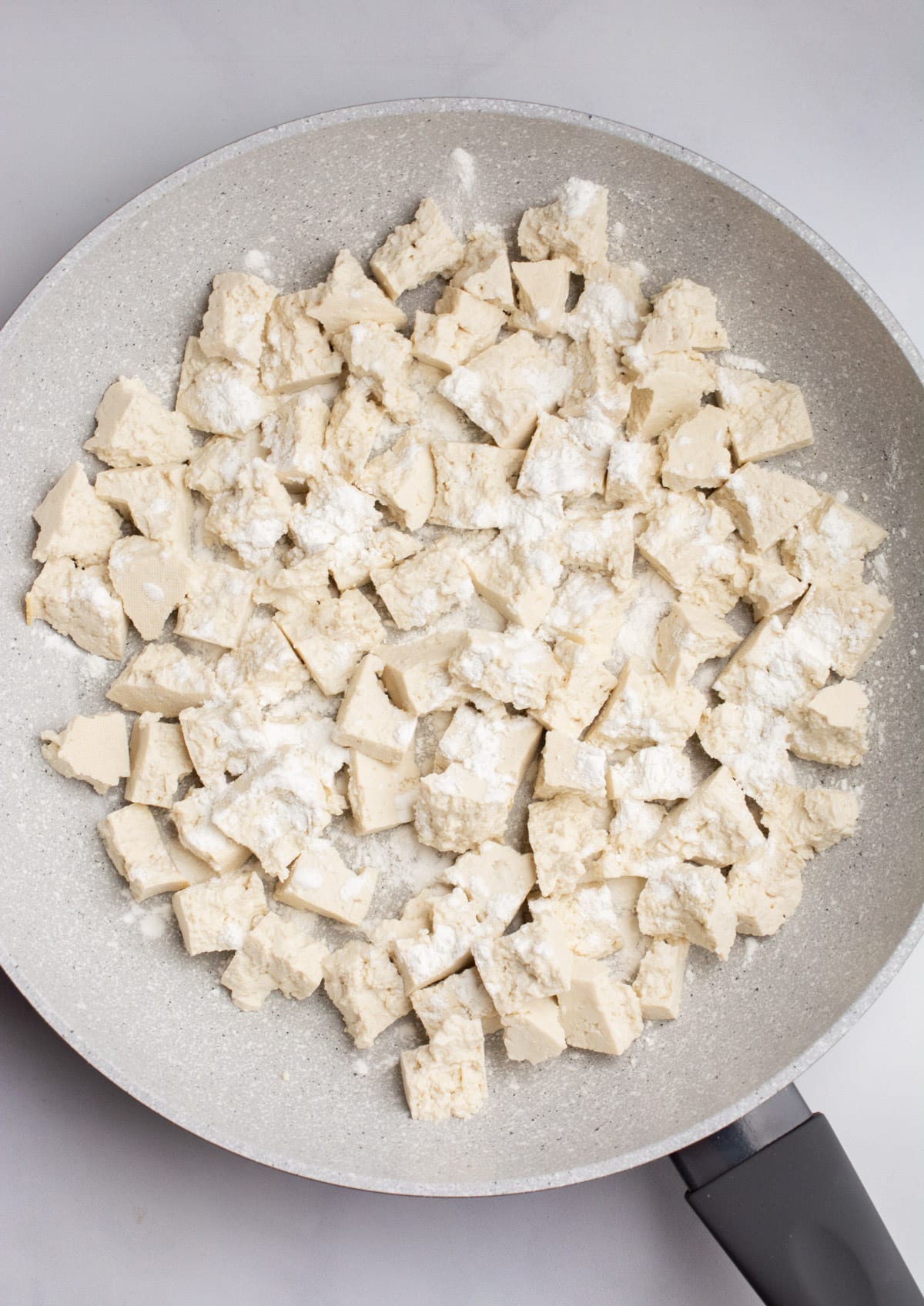 A pan of bite-sized pieces of tofu sprinkled with cornstarch.