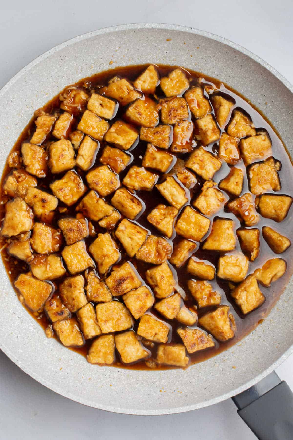 A pan with pan-fried tofu in homemade teriyaki sauce.