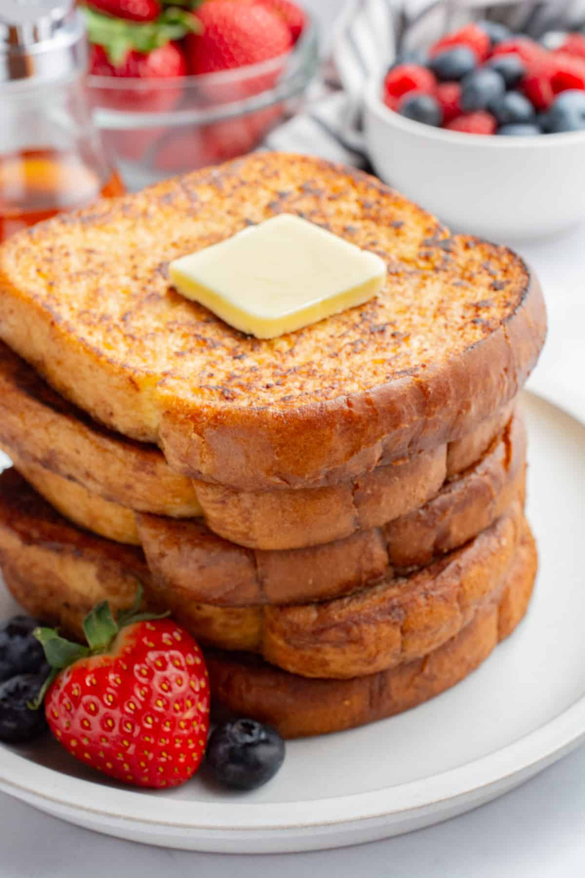 Vegan french toast stack topped with butter and a side of berries.