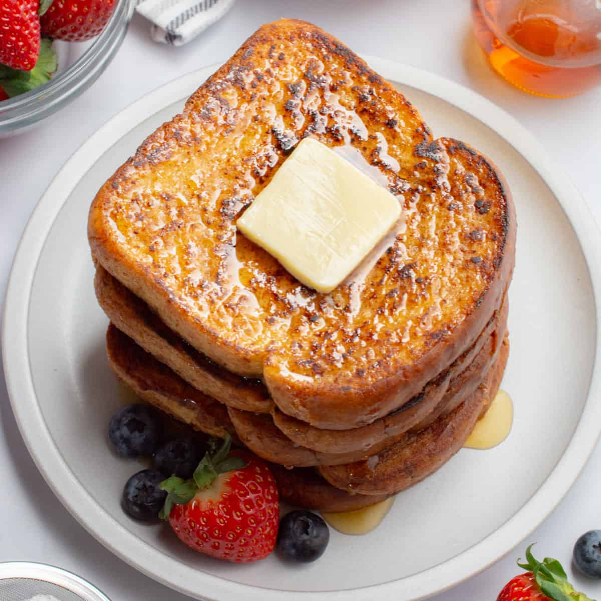 Vegan french toast topped with a butter square and syrup.