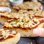 A hand grabbing a slice of vegan french bread cheese pizza.