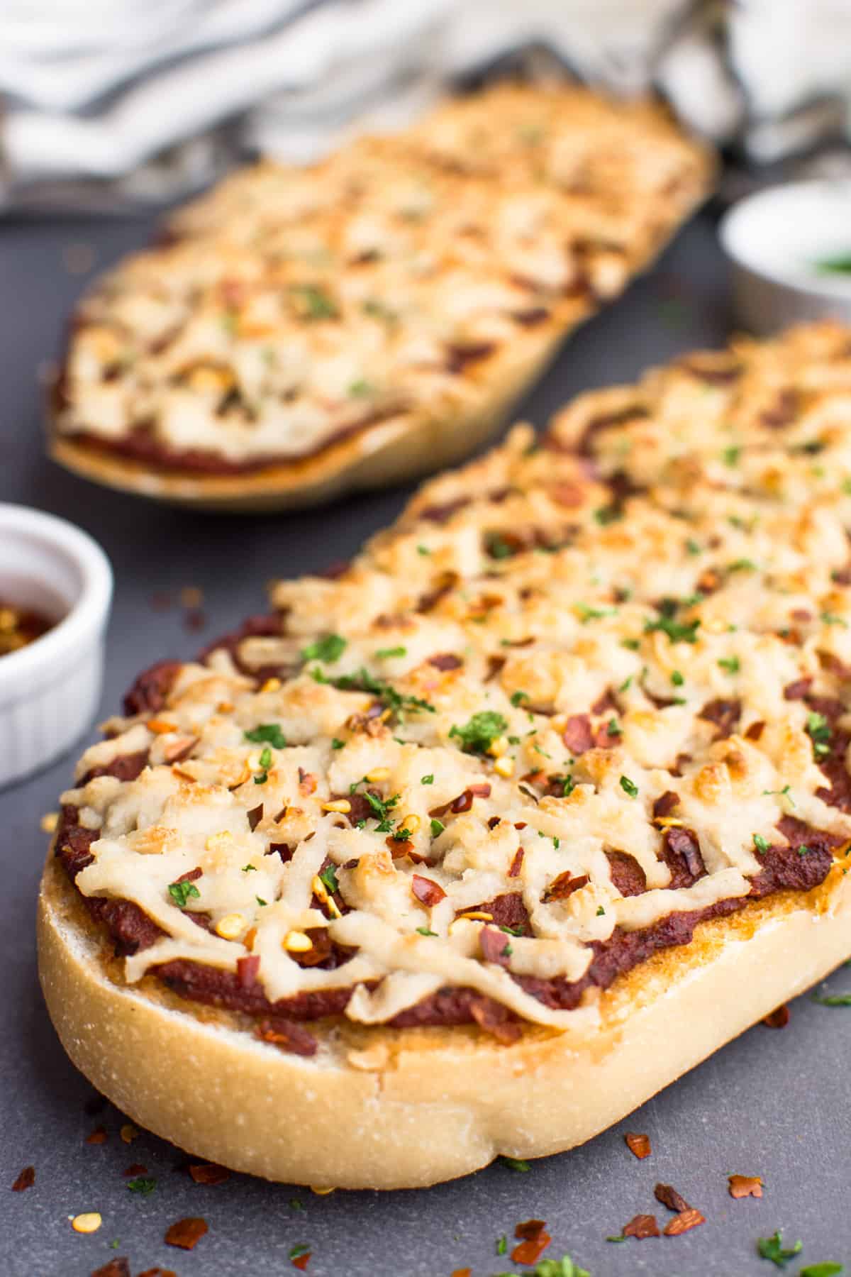 French bread pizza topped with shredded vegan cheese.