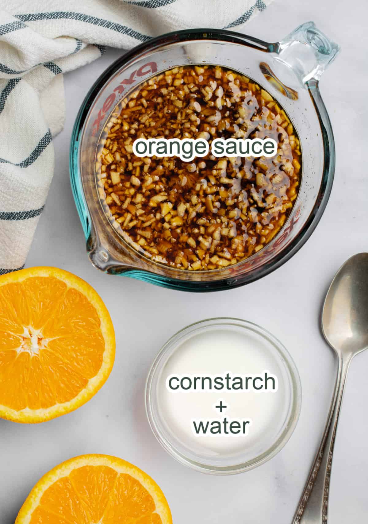 A measuring cup with sauce labeled orange sauce and a small bowl of white liquid labeled cornstarch plus water.