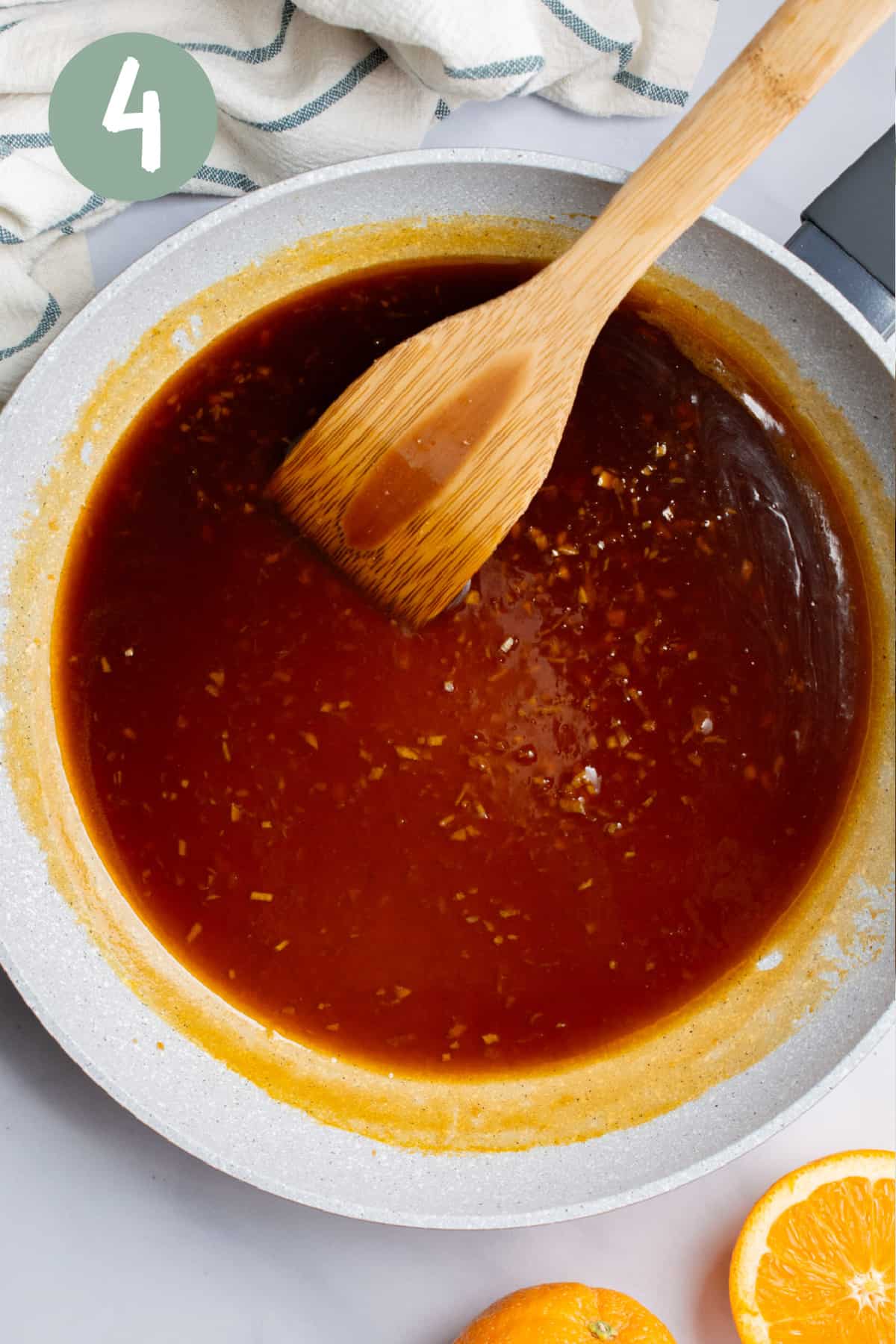 Orange sauce in a pan with a wooden spatula.