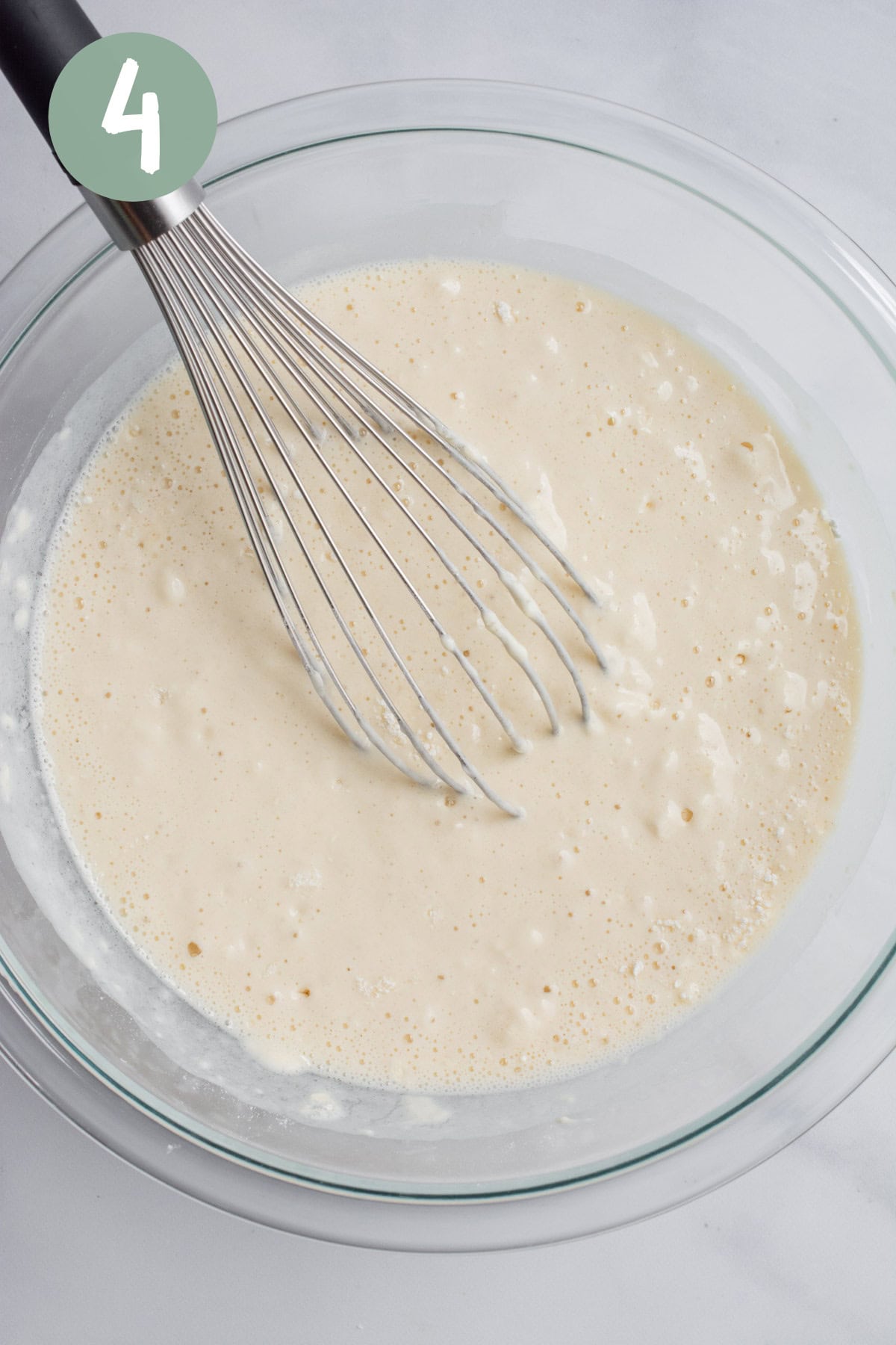Pancake batter in a glass bowl with a whisk.