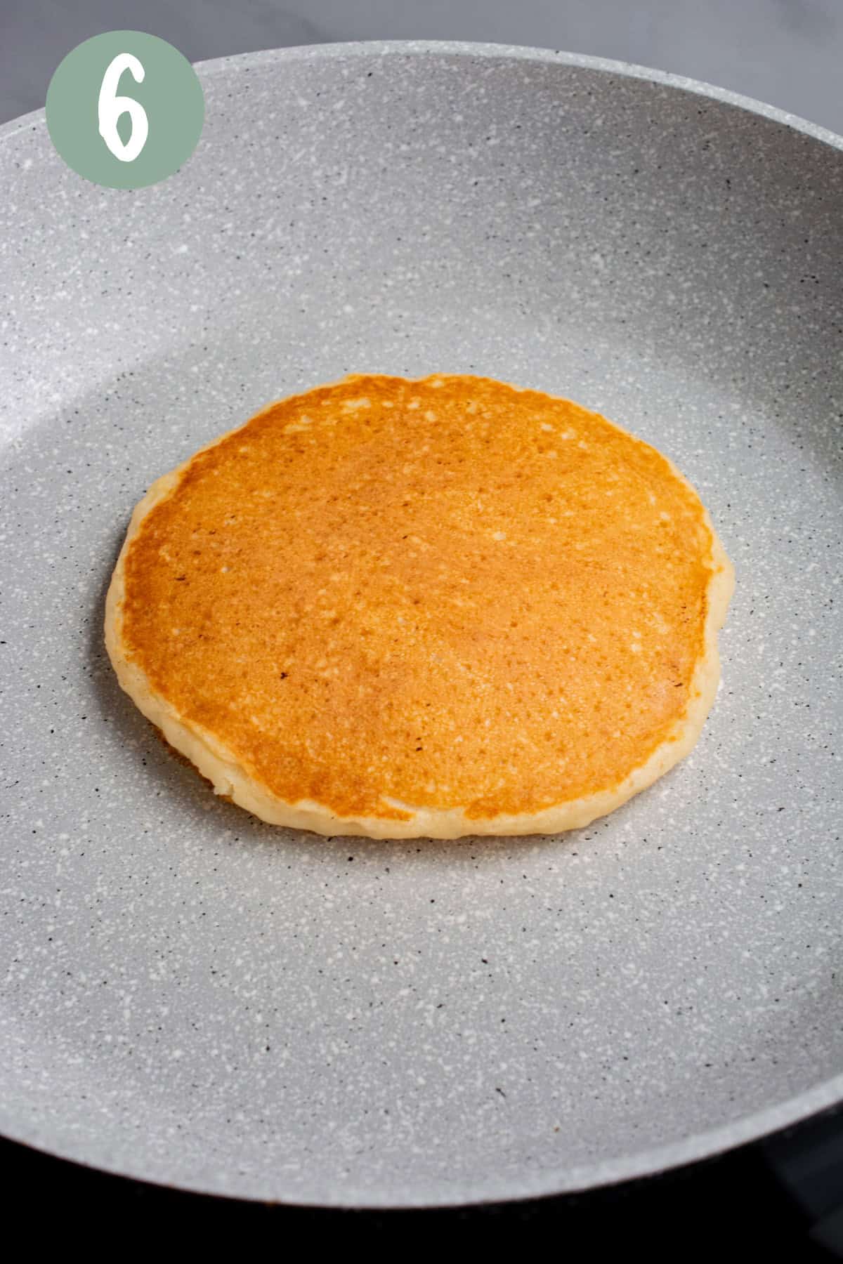 A pancake on a pan after flipping.