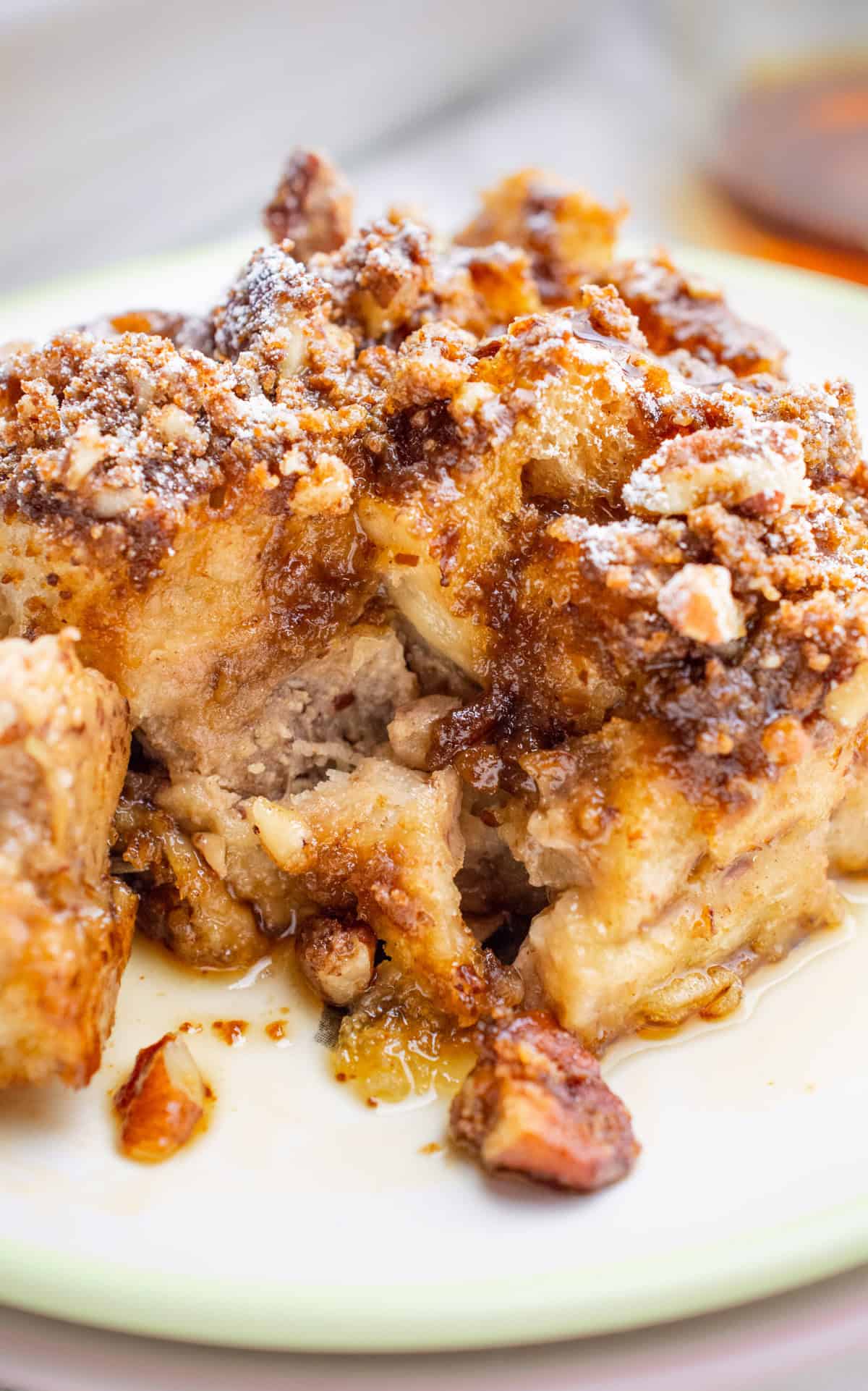 A slice of vegan french toast casserole topped with powdered sugar on a white plate.