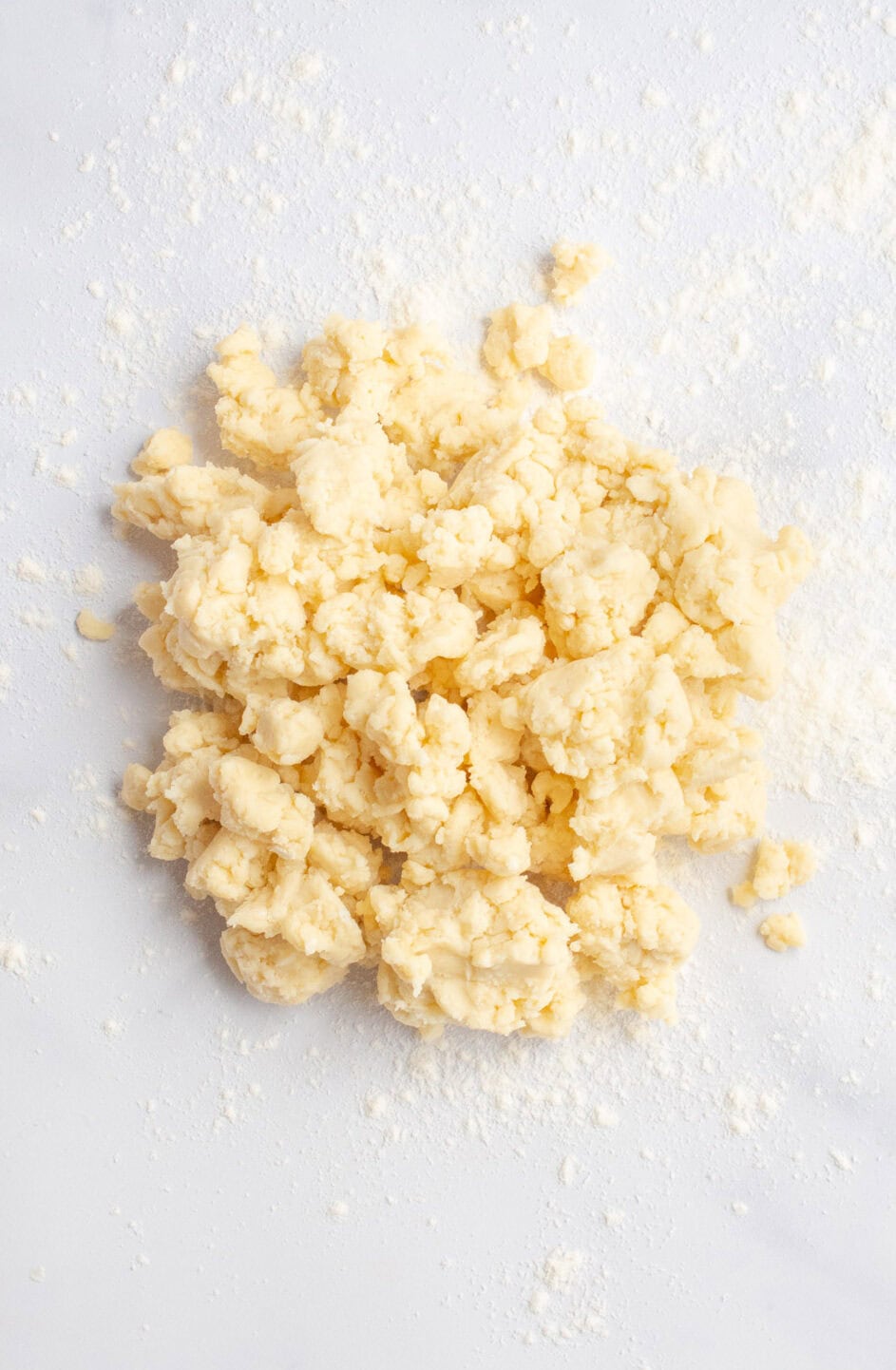 Crumbly pie dough on a marble countertop.