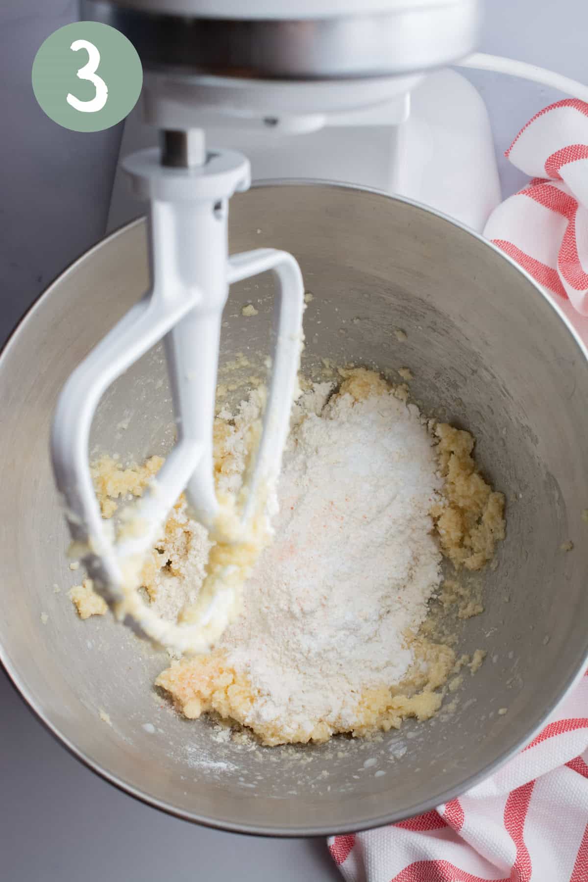 Flour, salt, and baking powder with wet ingredients for vegan sugar cookies in the bowl of a stand mixer.