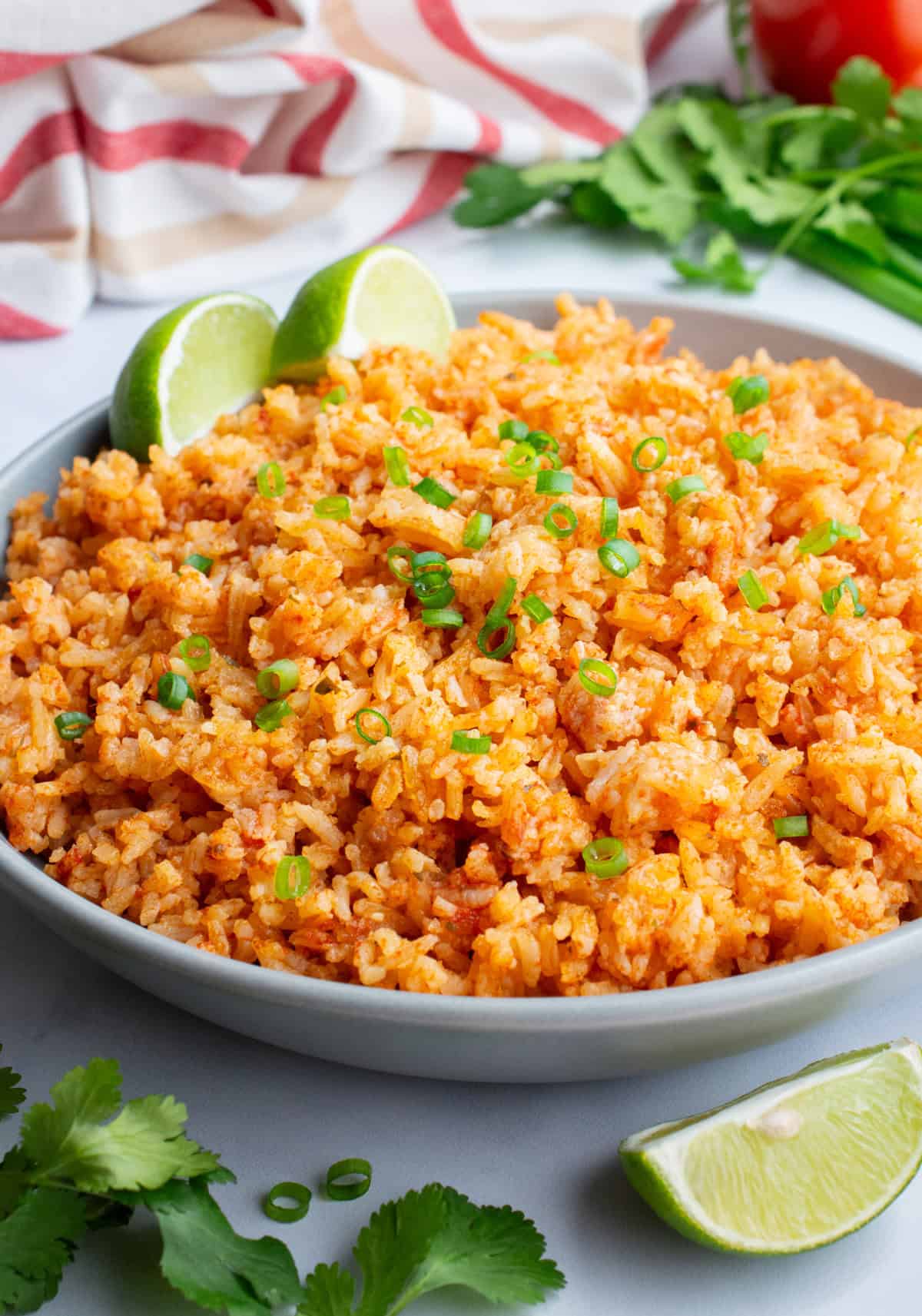 A bowl of Mexican rice with lime wedges and fresh cilantro.