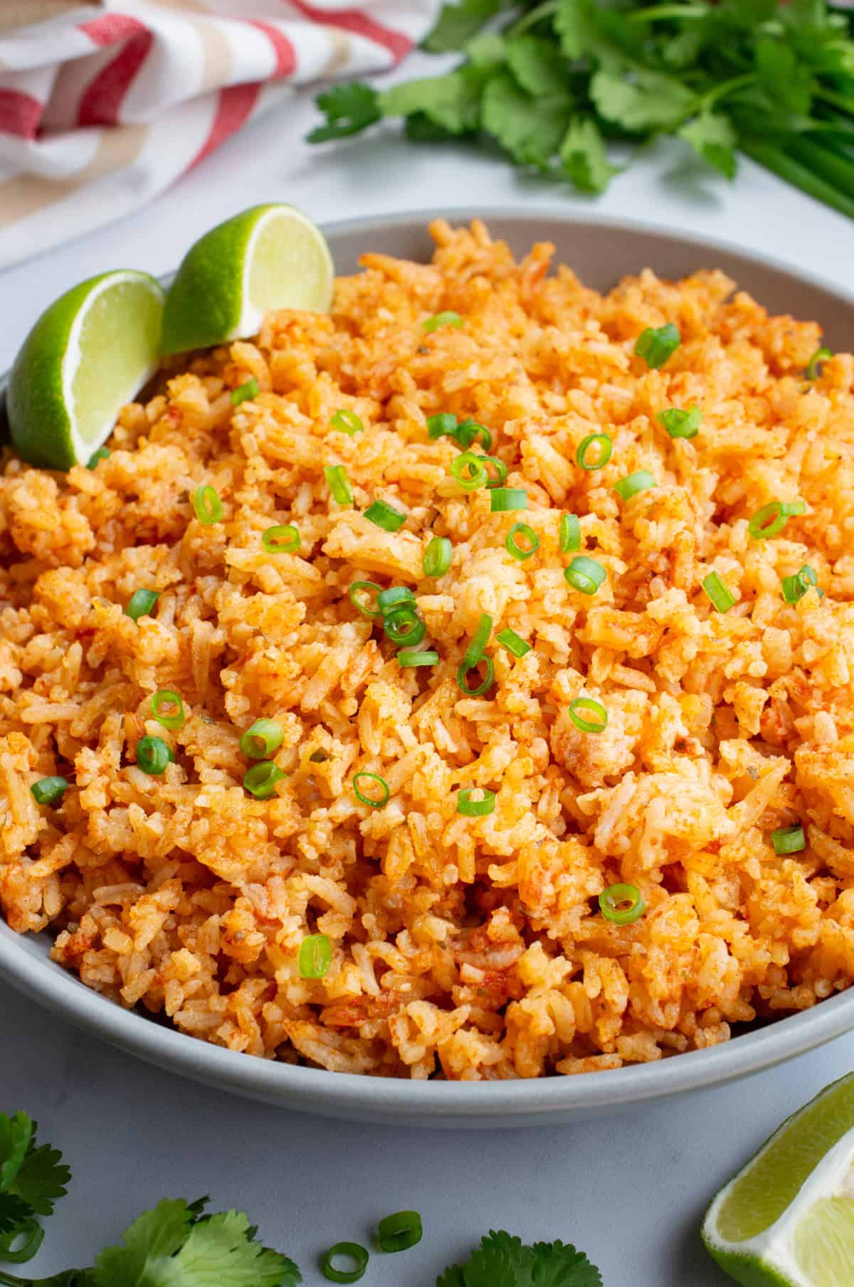A gray serving bowl with Spanish rice with two lime wedges.