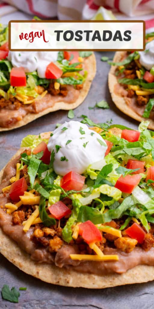 A crispy corn tortilla topped with refried beans, tofu meat crumble, vegan cheese, shredded lettuce, diced tomatoes, a dollop of dairy-free sour cream and freshly chopped cilantro.