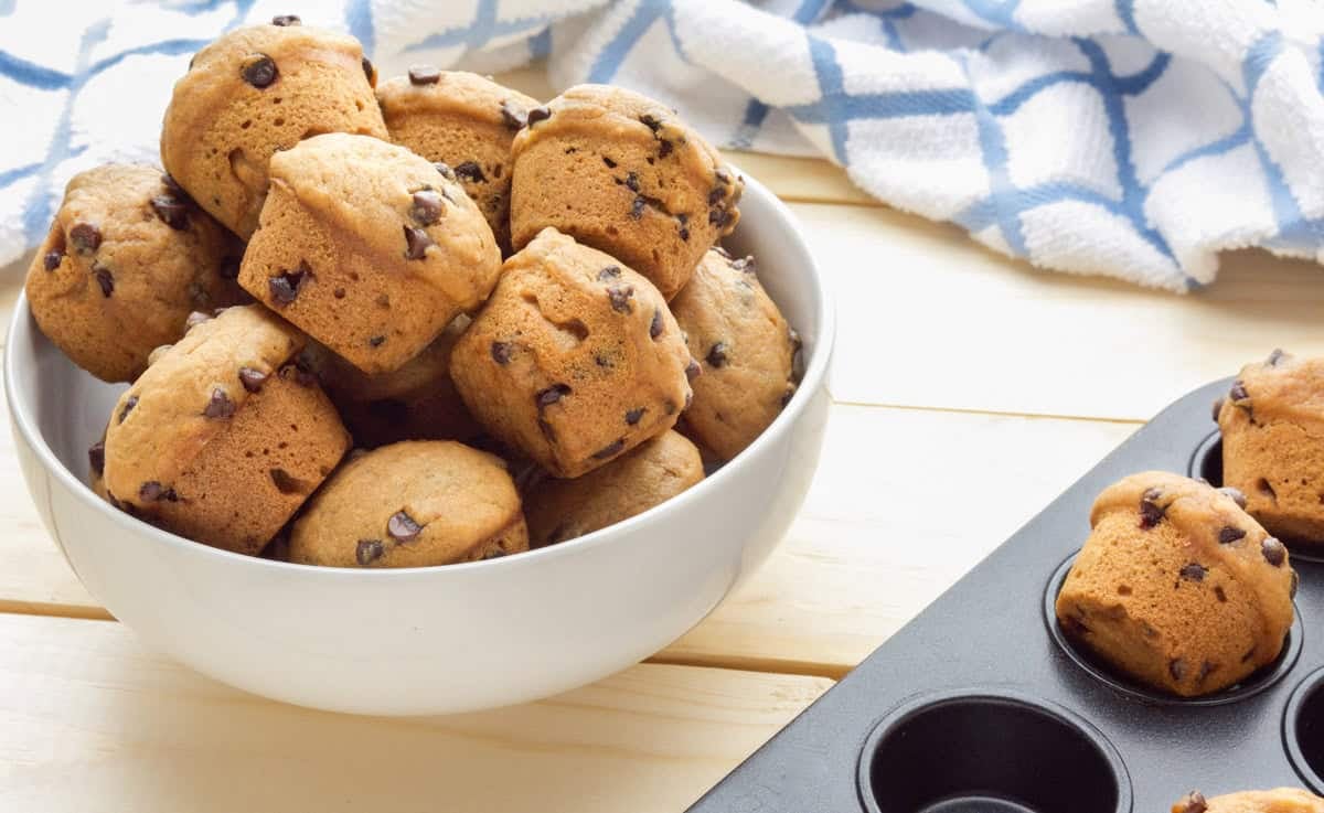 Vegan chocolate chip muffins in a bowl and a muffin tin.