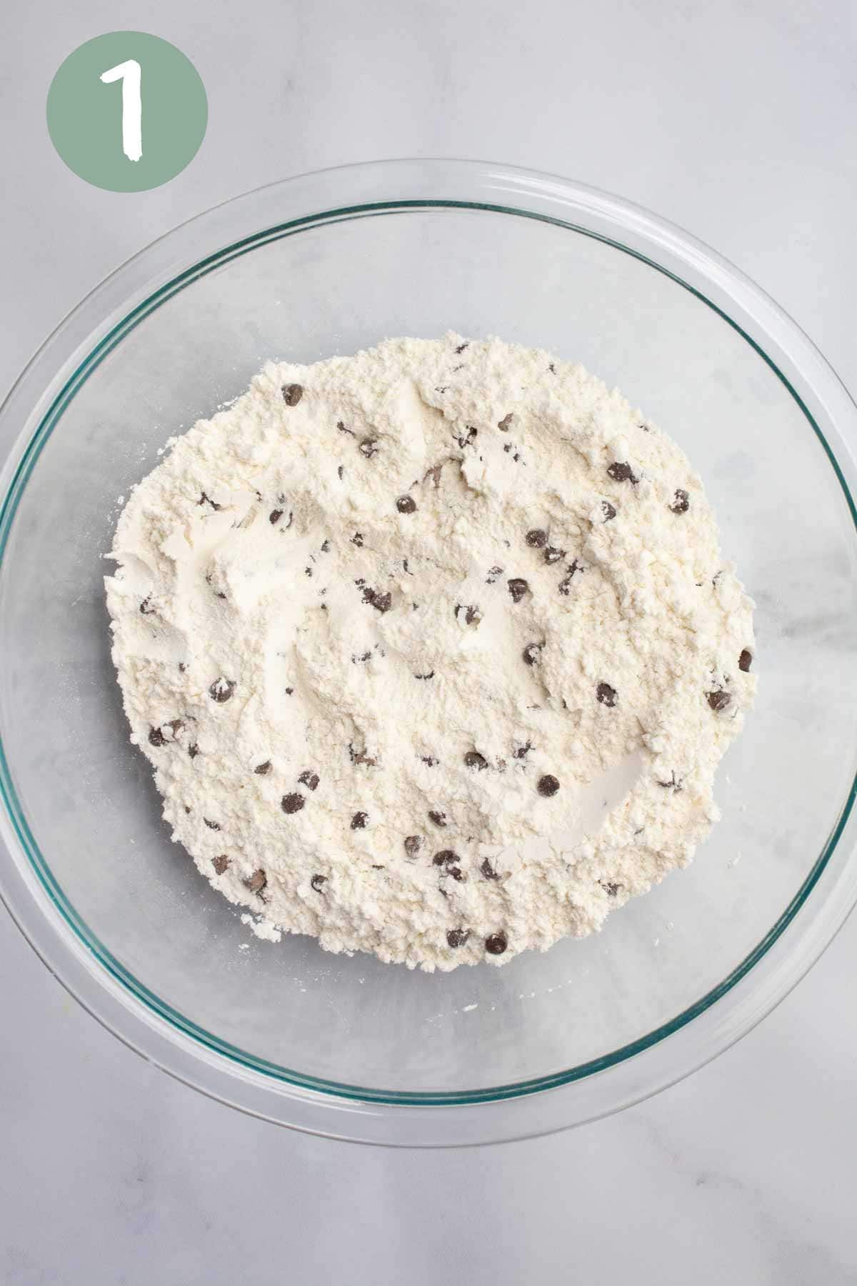 A glass bowl with flour and chocolate chips.