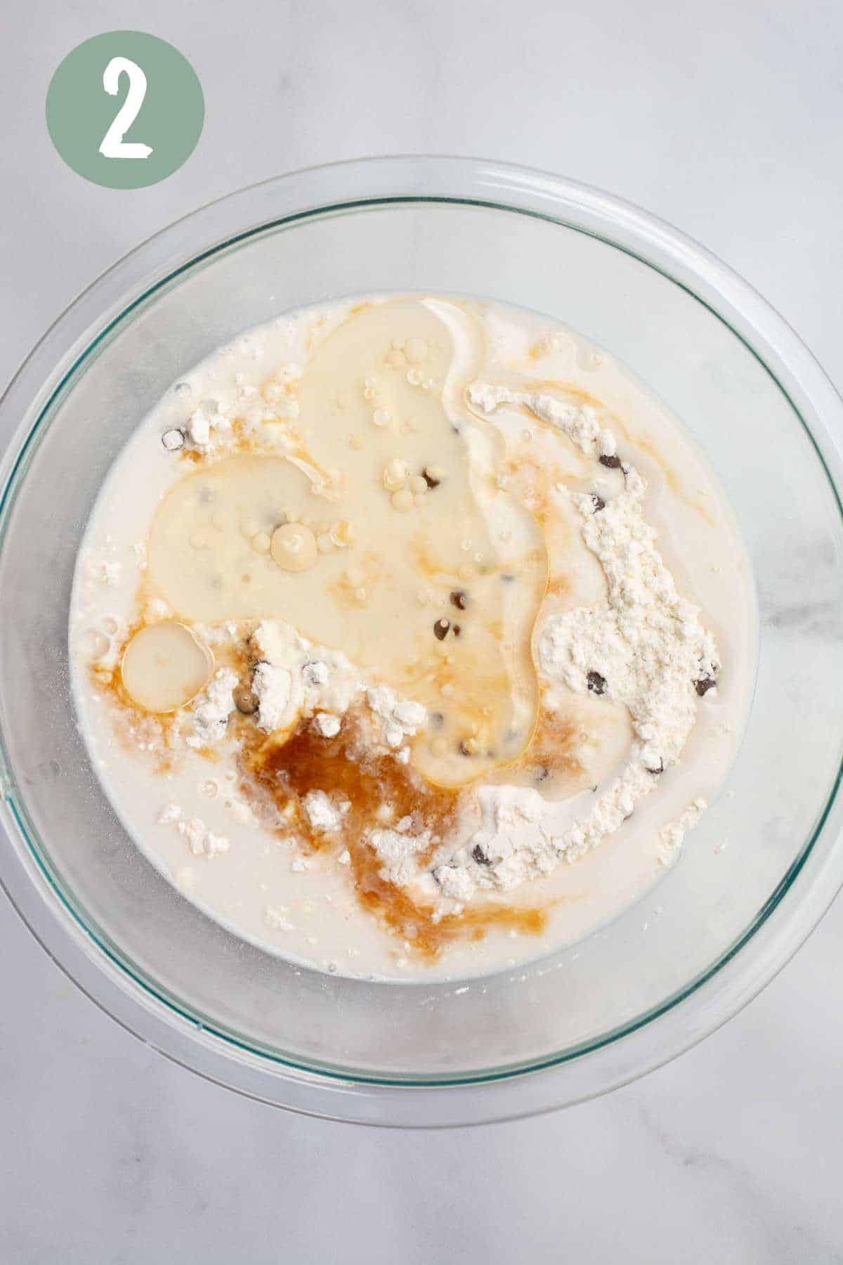 A glass bowl of dry muffin ingredients with wet ingredients poured on top.