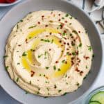 Homemade hummus topped with oil, red pepper flakes, and finely chopped parsley.