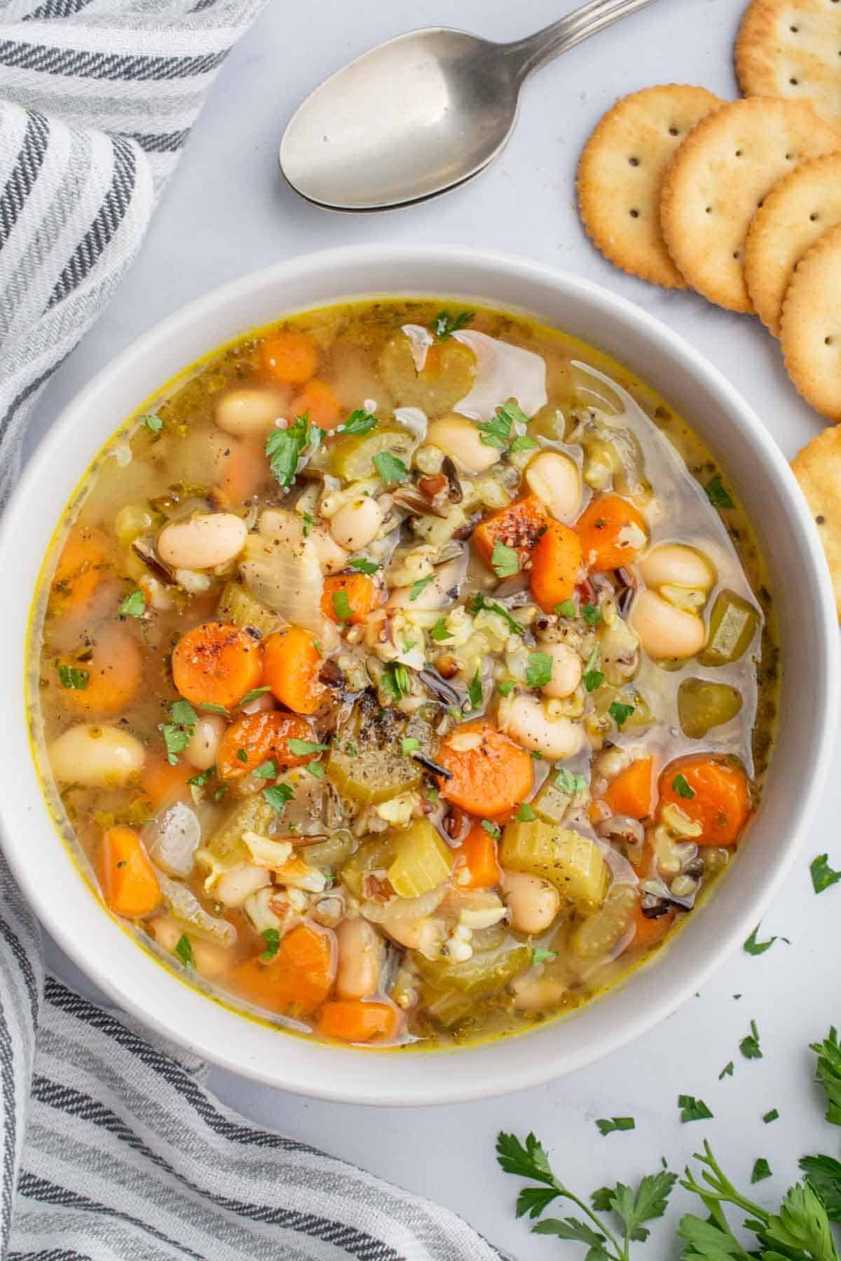 A bowl of wild rice soup served with round crackers.