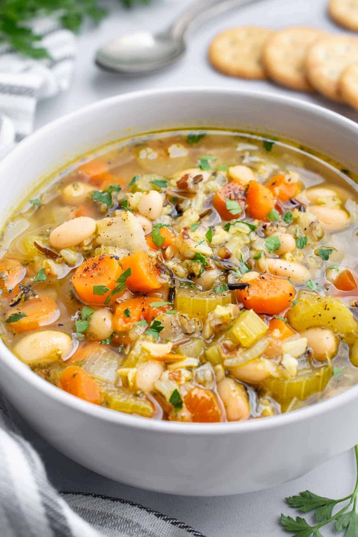 A bowl of wild rice soup with carrots, onion, celery, and white beans.