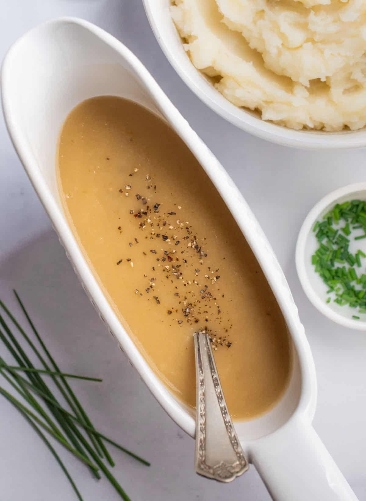 A gravy boat filled with onion gravy and topped with fresh black pepper.
