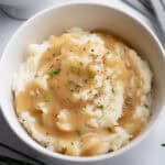 Mashed potatoes and gravy in a white bowl.