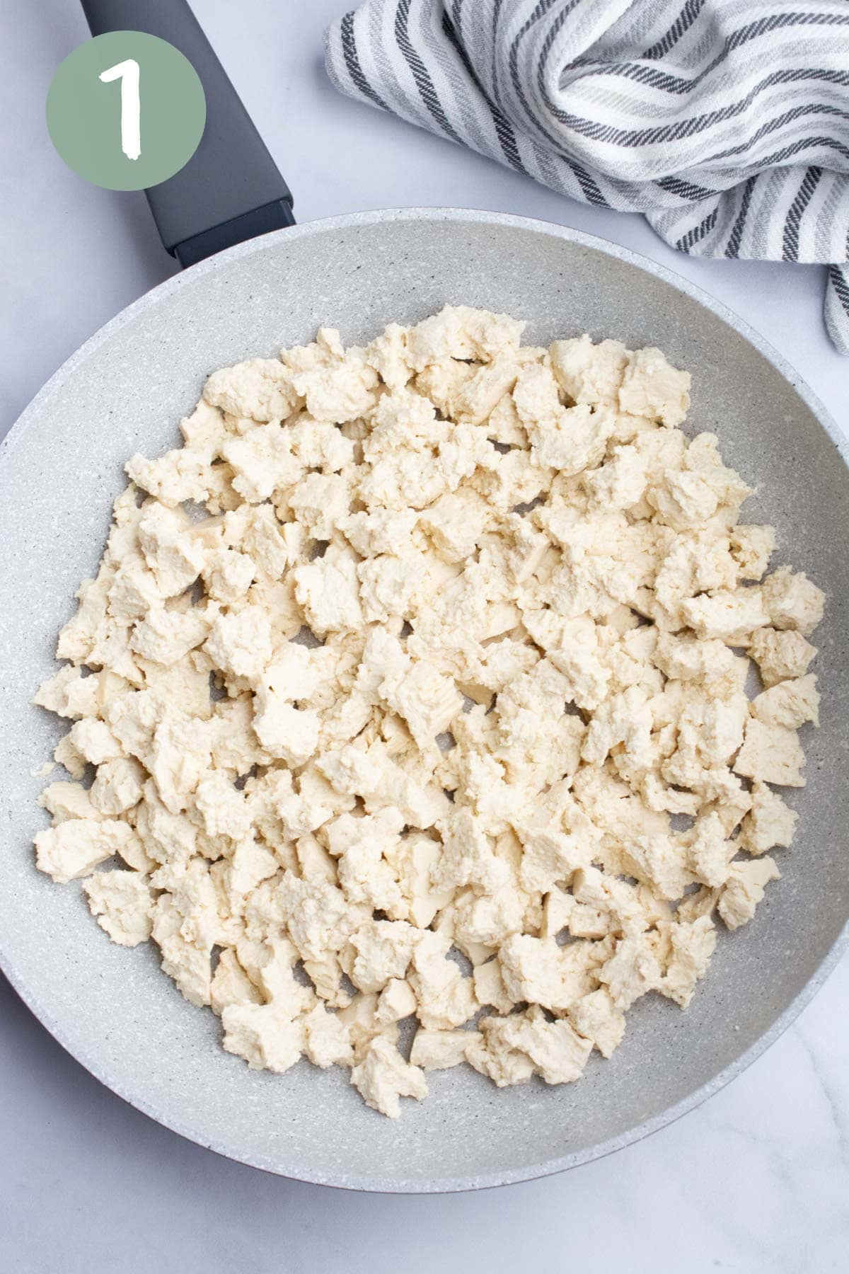 Raw tofu broken into pieces in a pan.