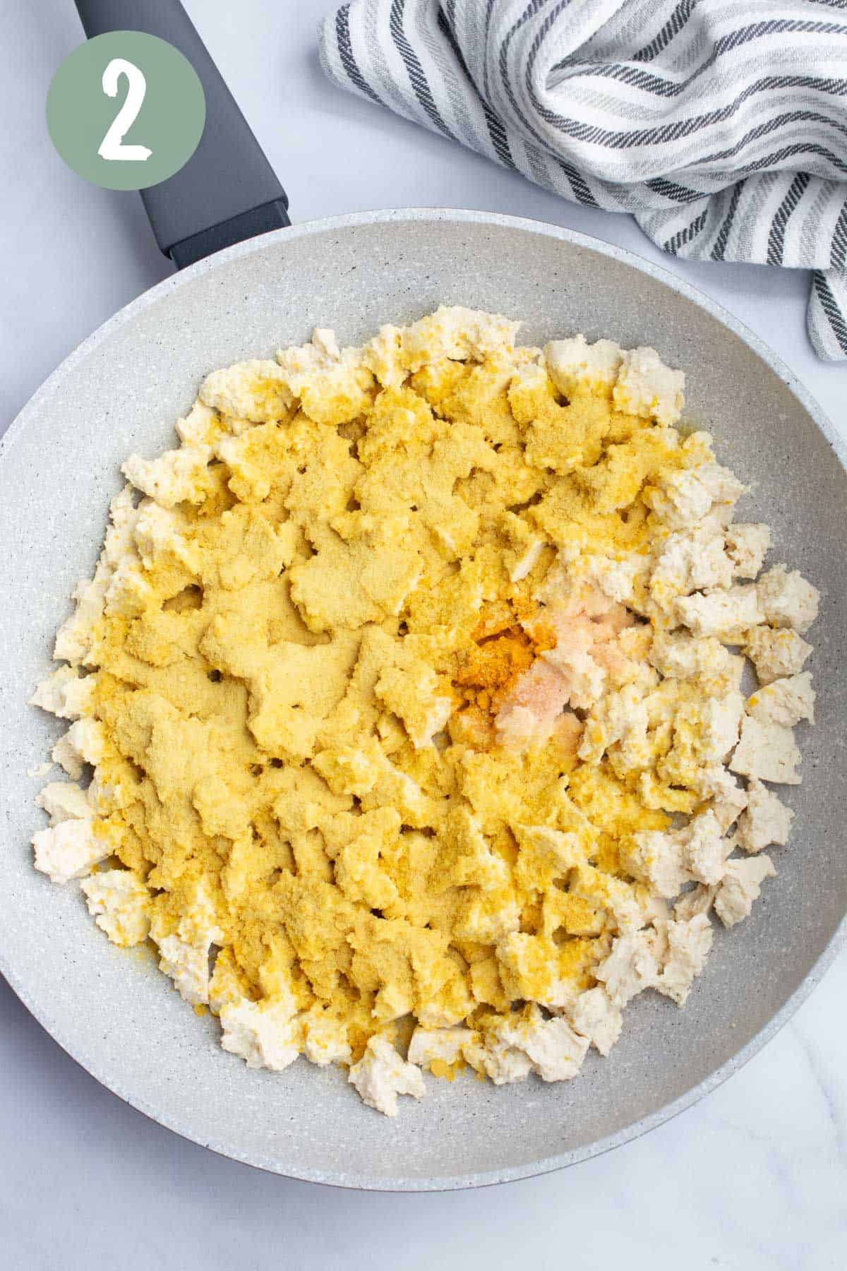 Raw tofu in a pan with seasonings sprinkled on top.