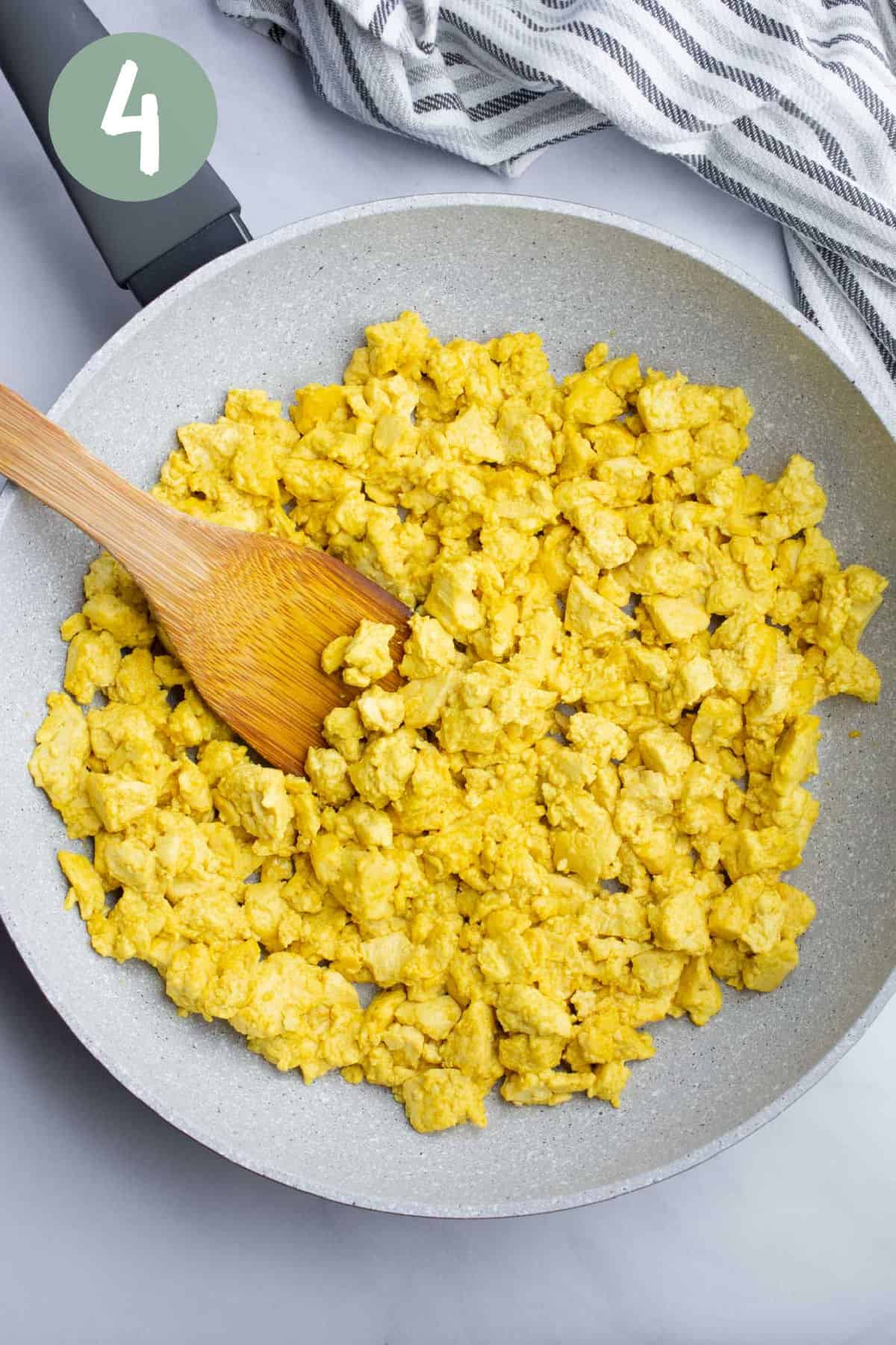Tofu scramble in a pan with a spatula.