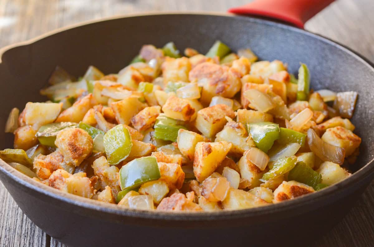 Diced potatoes with bell pepper and onion in a cast-iron skillet.