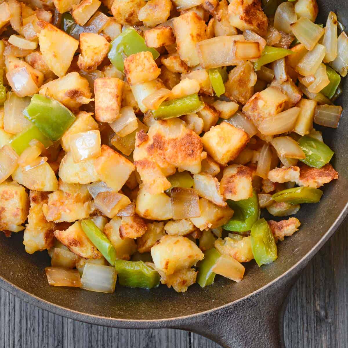 pan fried potatoes, bell peppers, and onion in a cast-iron skillet.