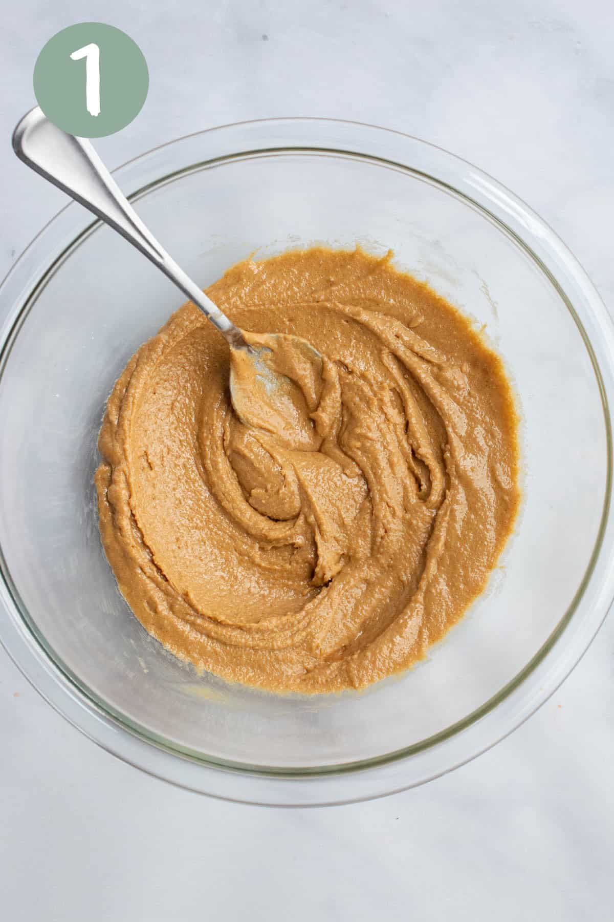 A glass bowl with peanut butter and sugar mixed.