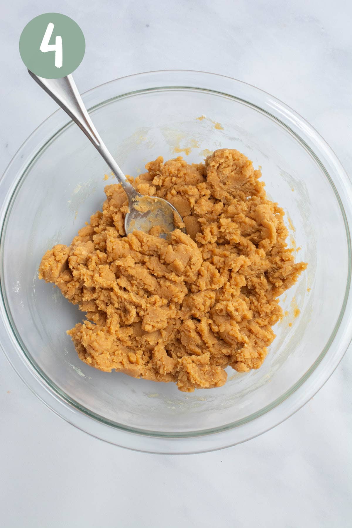 Vegan peanut butter cookie dough in a glass bowl with a spoon.