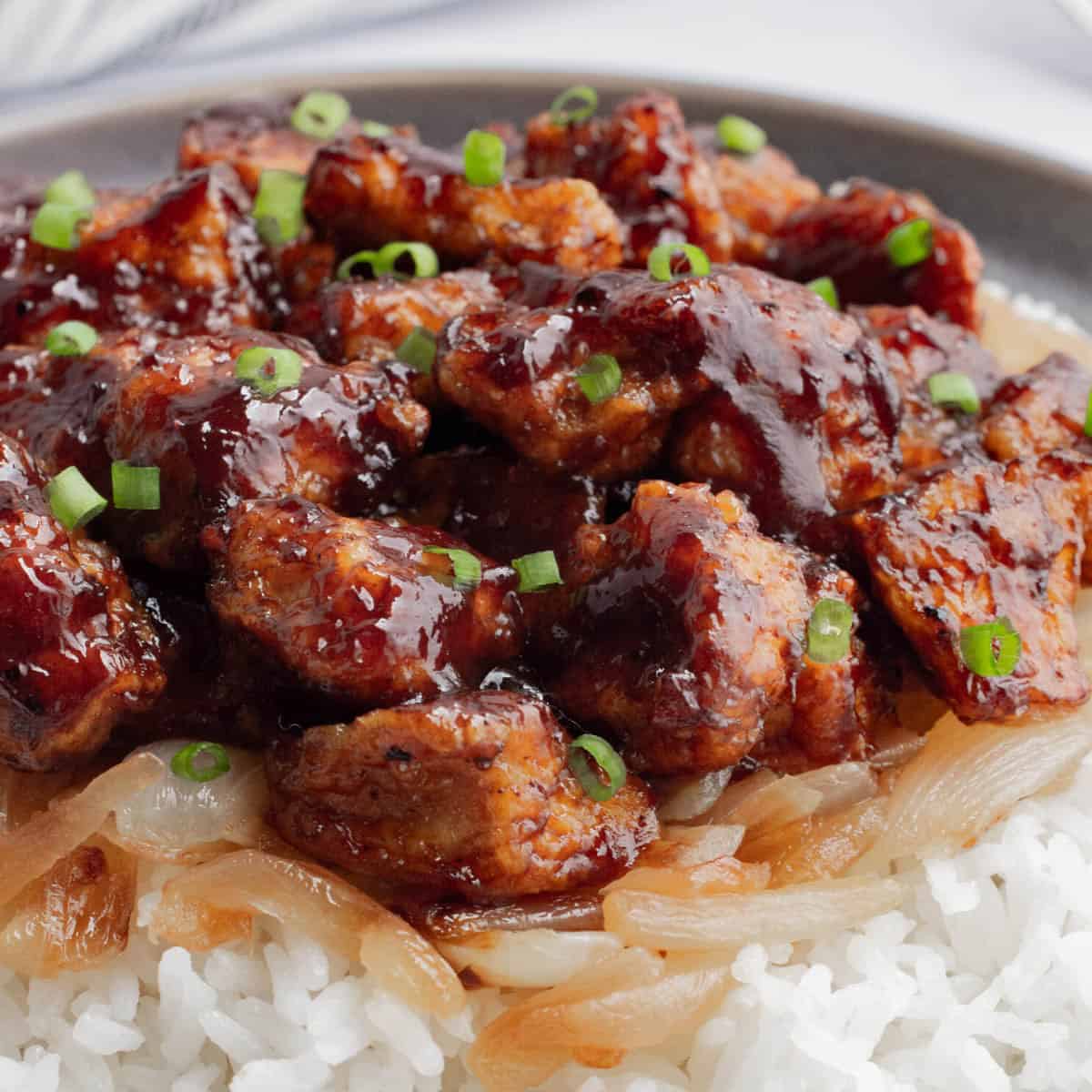BBQ tofu on a bed of white rice with caramelized onions.