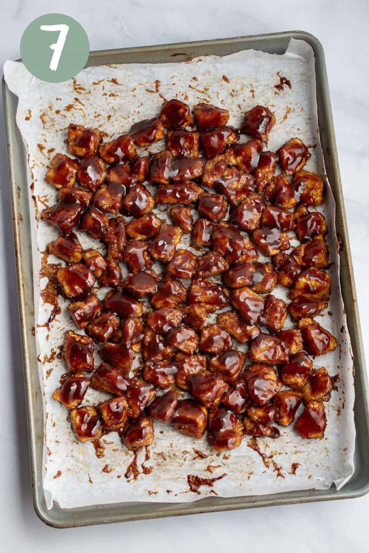 Tofu on a baking sheet covered in BBQ sauce.