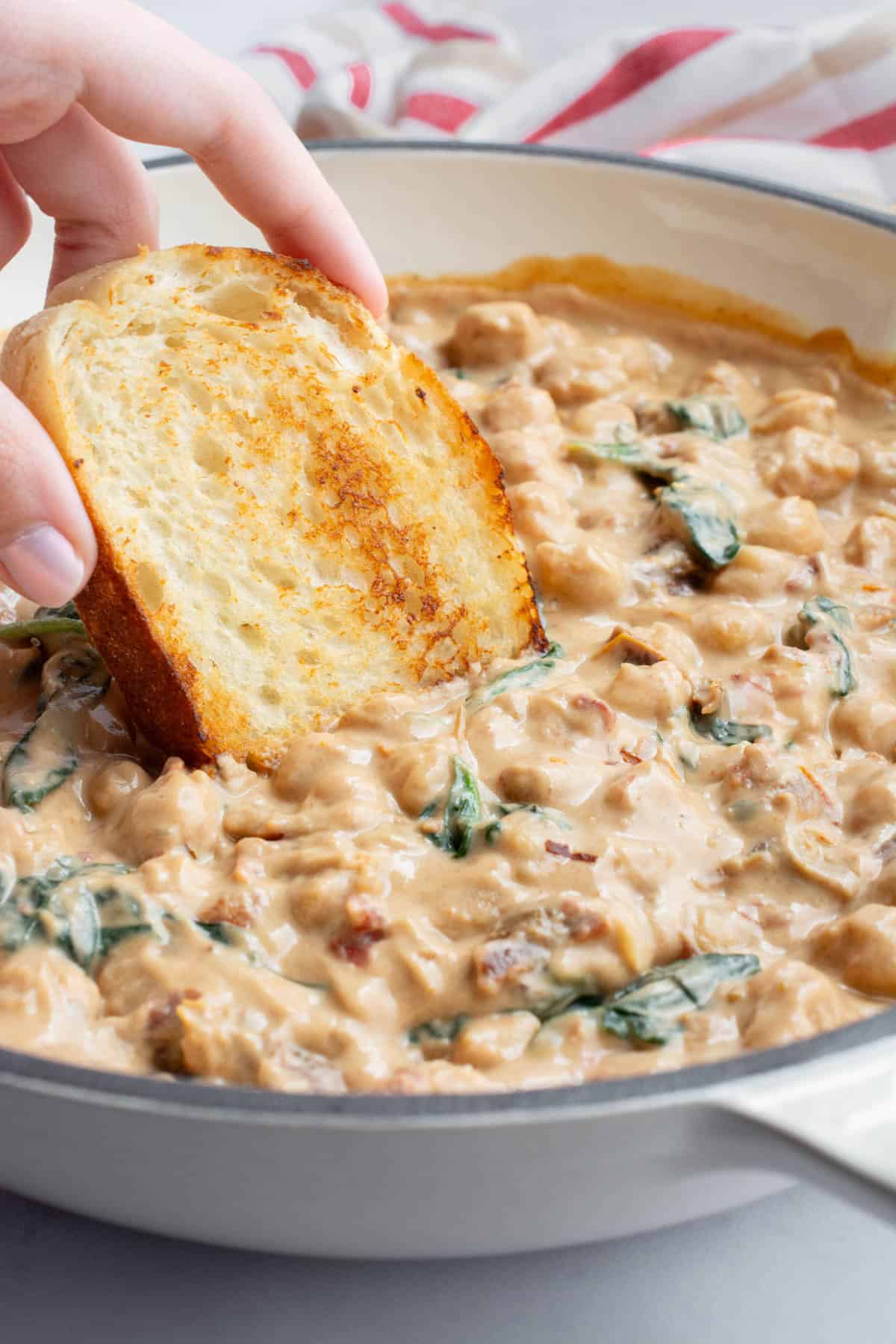Creamy Tuscan chickpeas with toasted bread being dipped in.