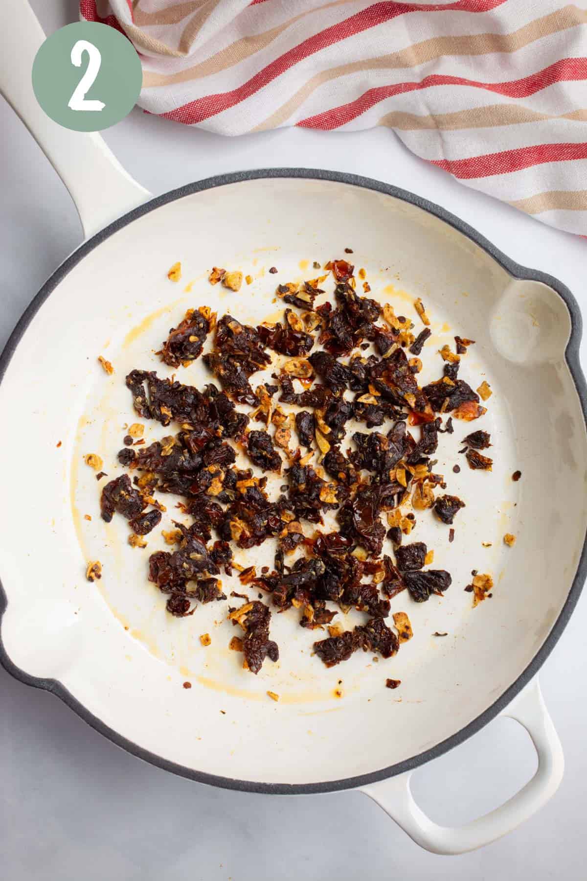 Sautéed sun-dried tomatoes, fresh garlic, and seasonings in a pan.